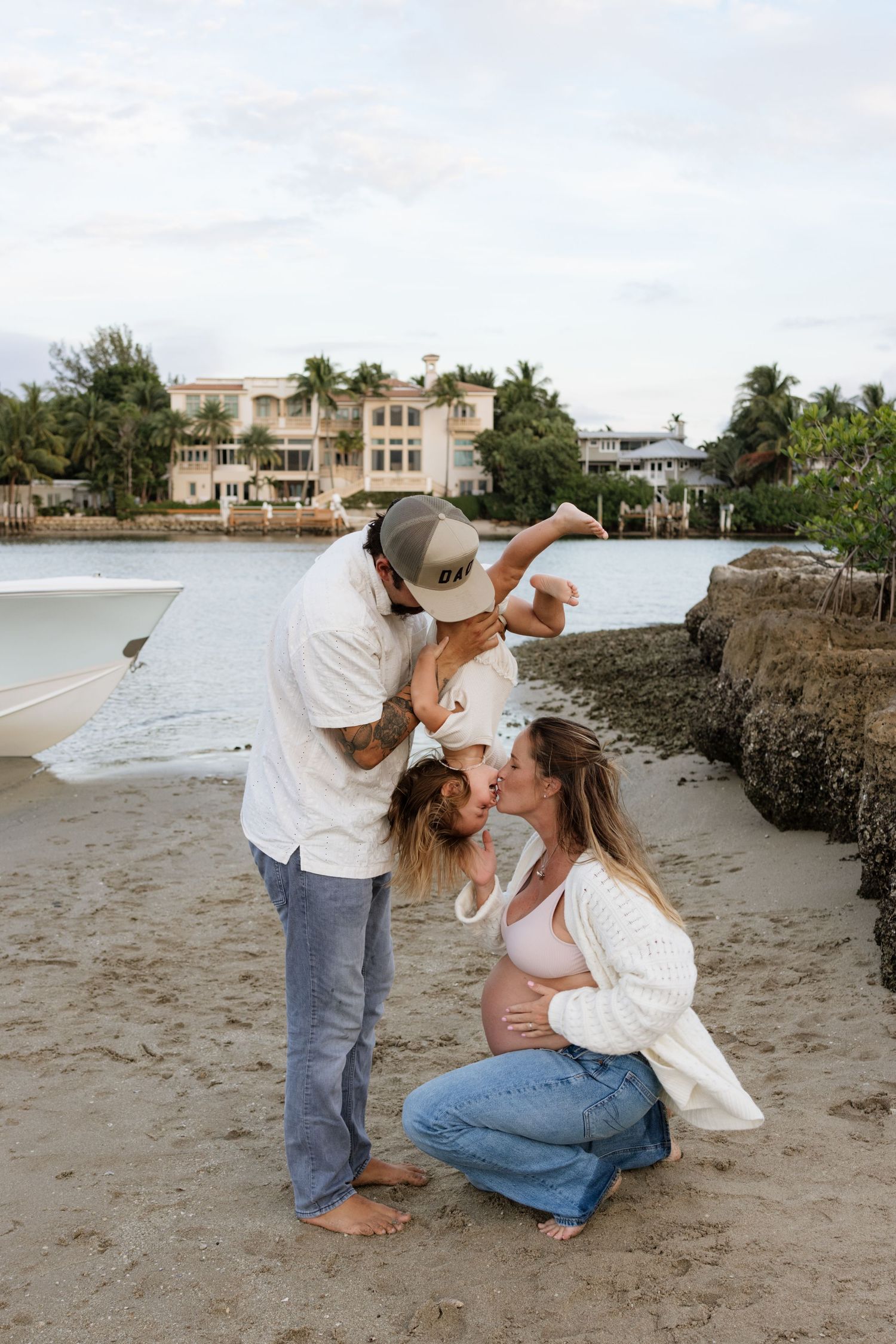Intimate family portraits on a beach with waterfront homes visible in the background.