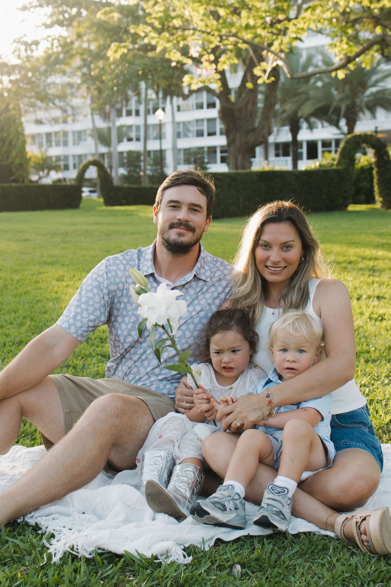 Family relaxing together on grass during golden hour photoshoot in coordinated outfits.