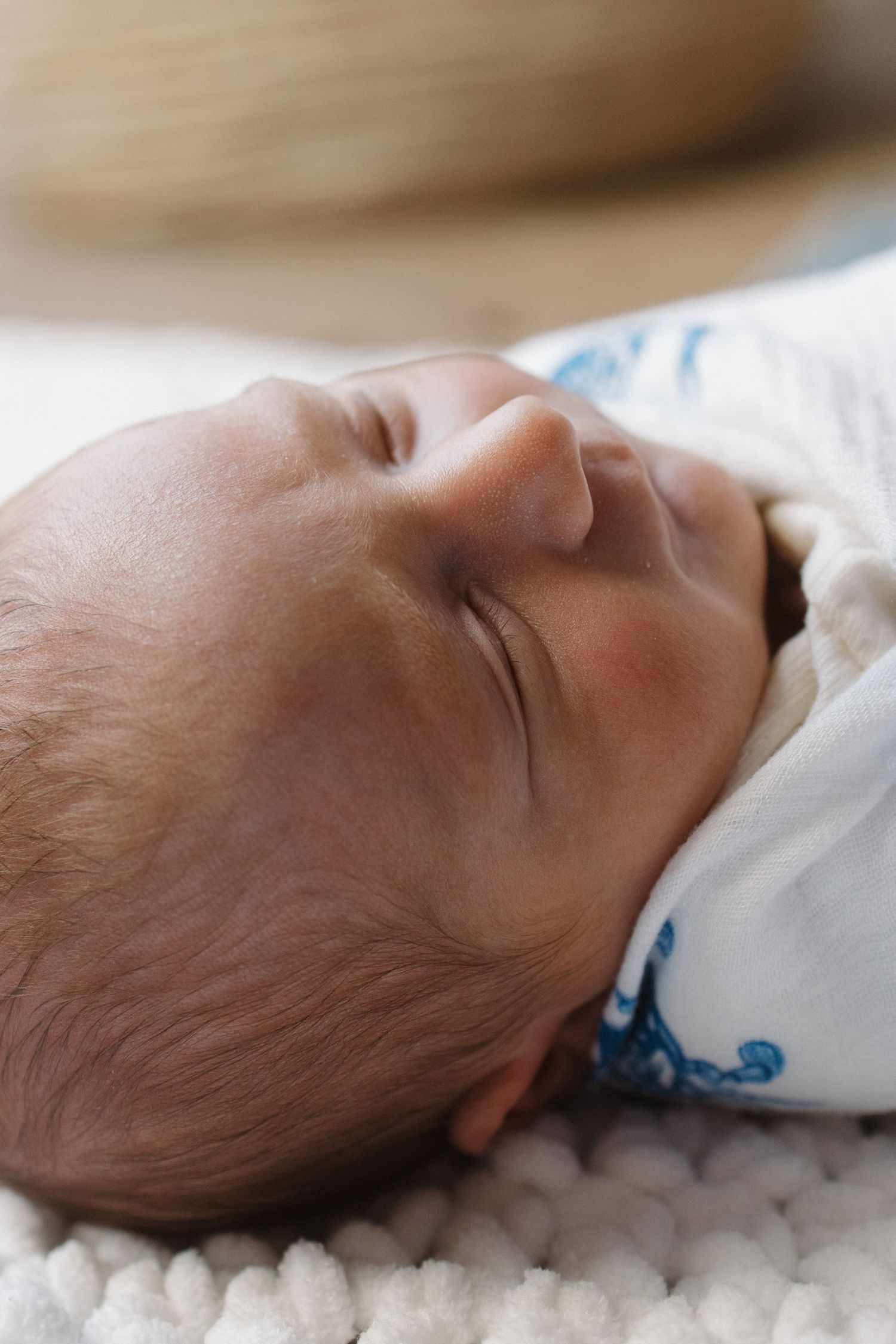 A sleeping newborn baby rests peacefully on white bedding.