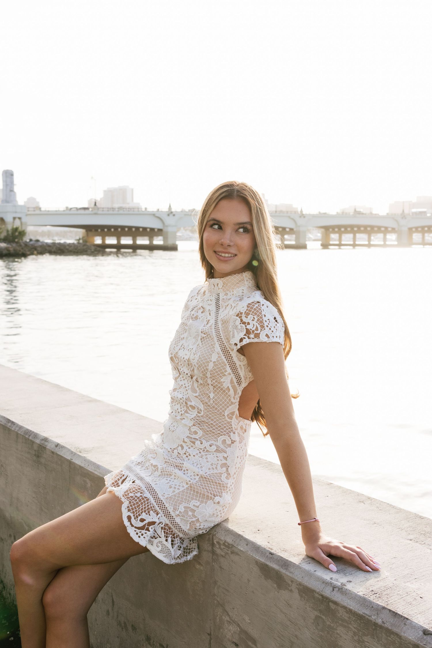 Seaside fashion photography with urban waterfront and bridge in background.