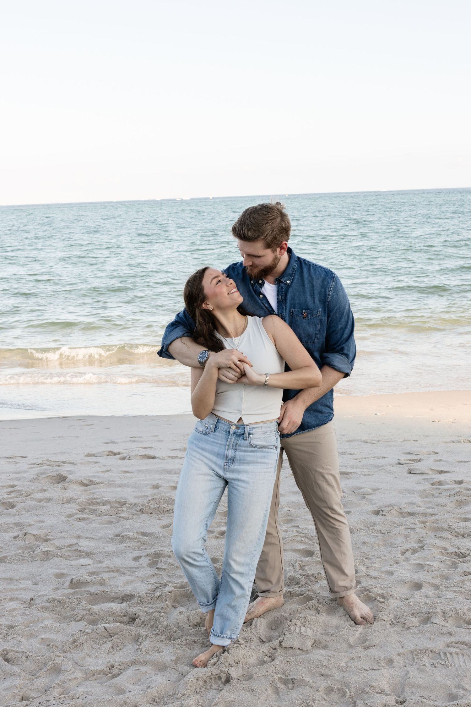 Romantic beach photoshoot with casual denim and natural coastal lighting.