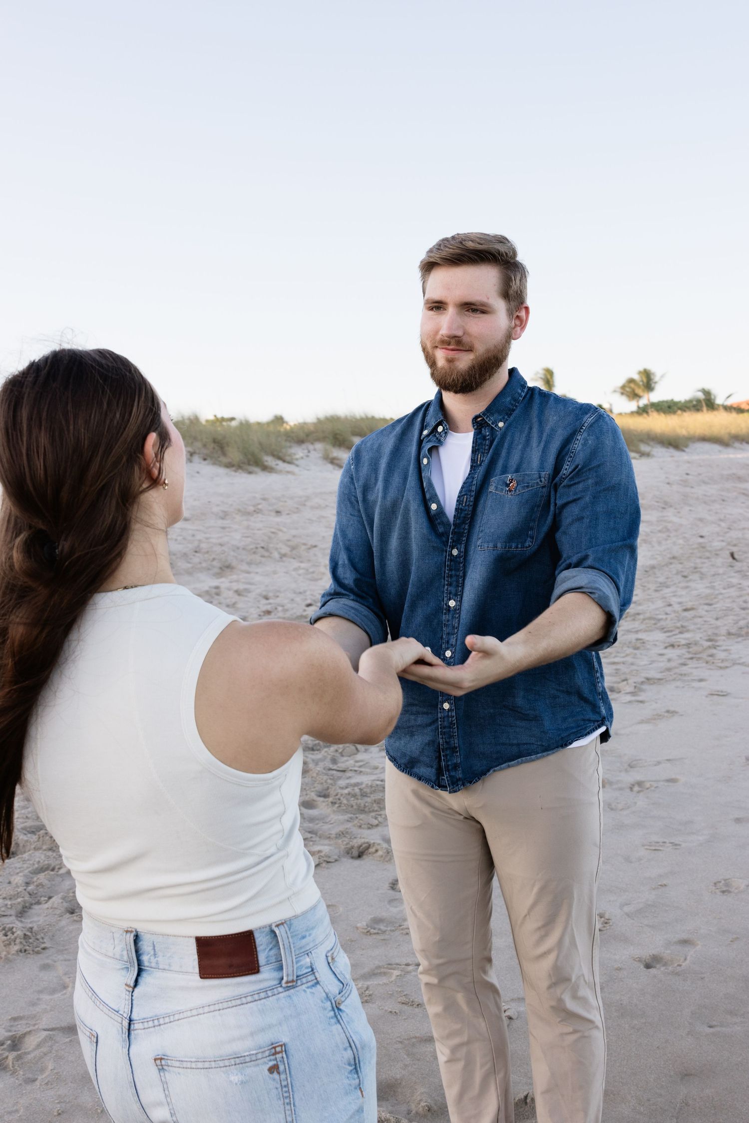 A couple practices dance moves together on a sandy beach.