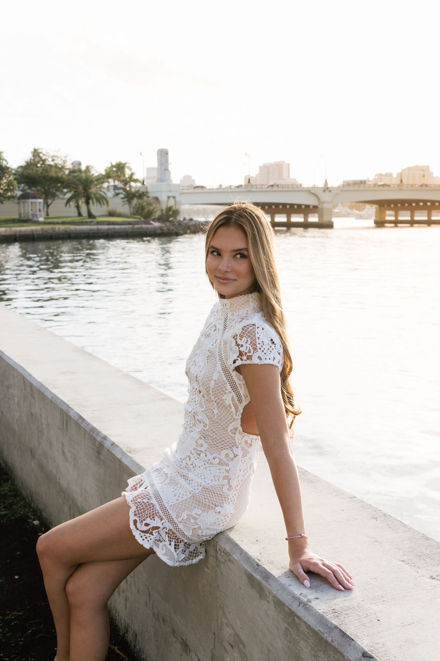 Sunset photoshoot by waterfront featuring white lace outfit.