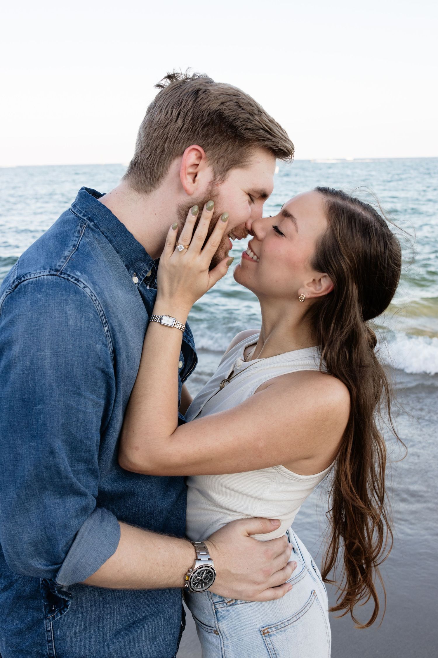 A tender moment shared between a couple during a beach photoshoot.