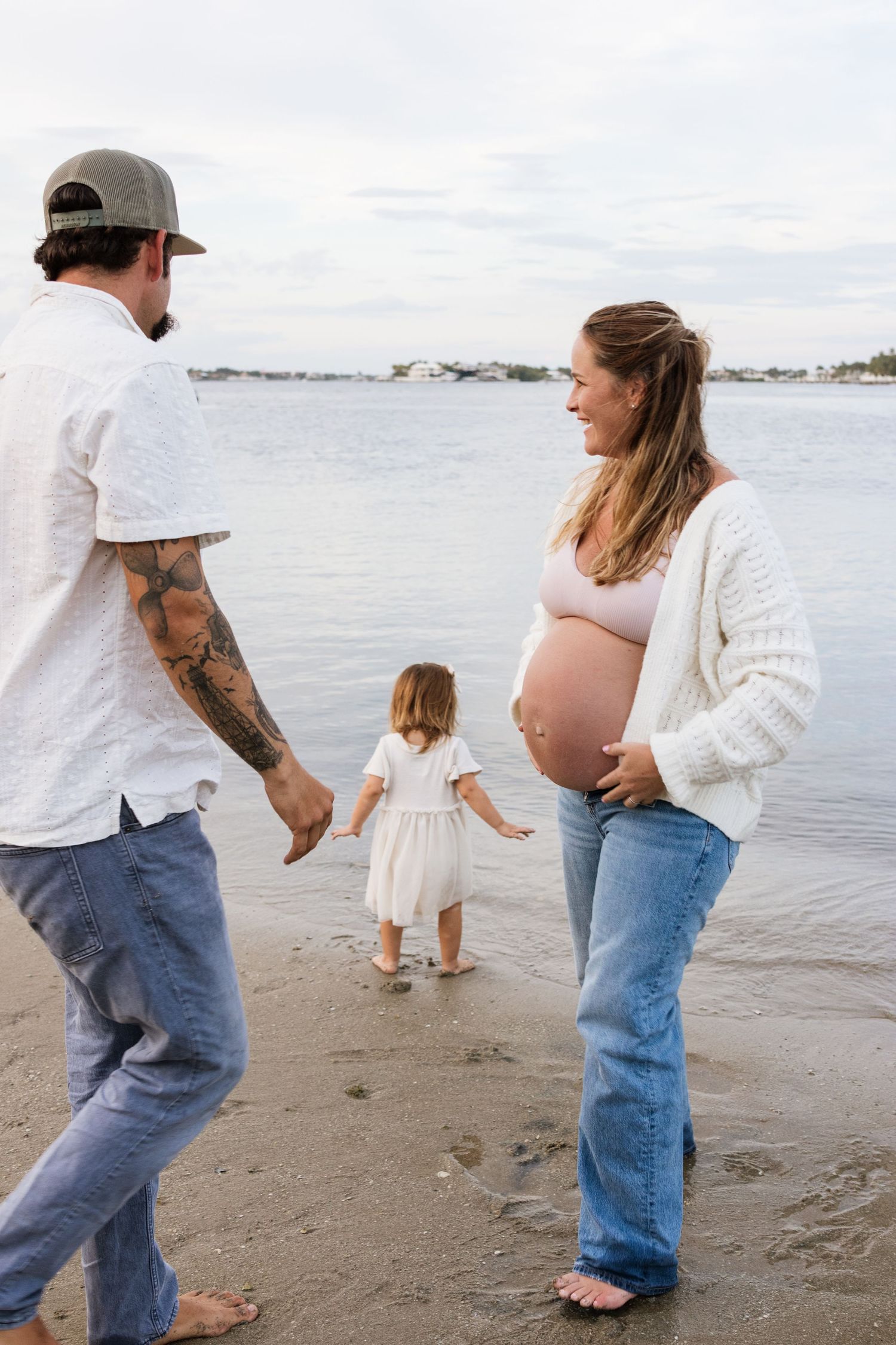 Family walking together on a sandy beach at sunset holding hands and enjoying the ocean view.