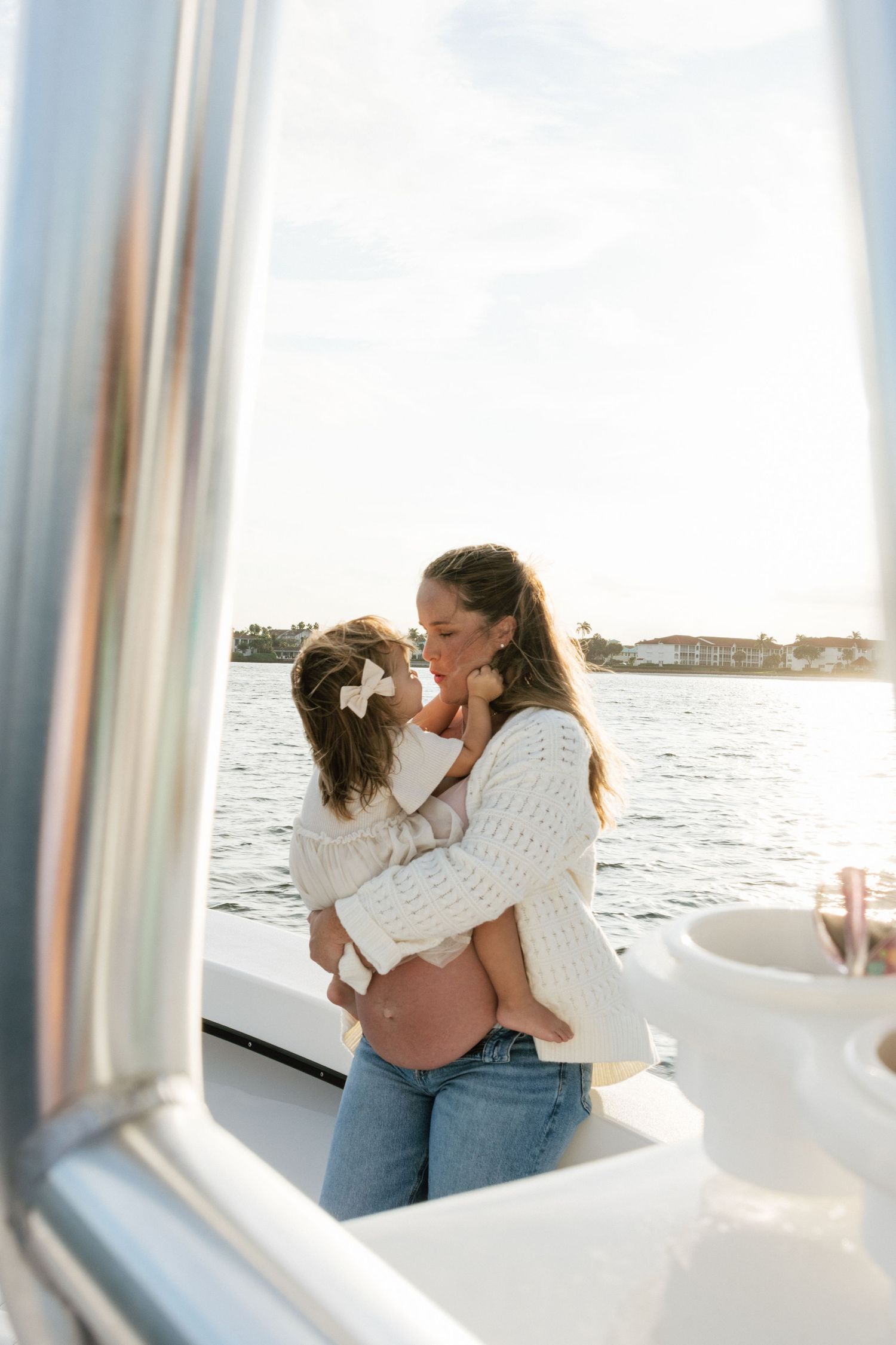 An intimate family moment captured on a boat with water and buildings visible in background.