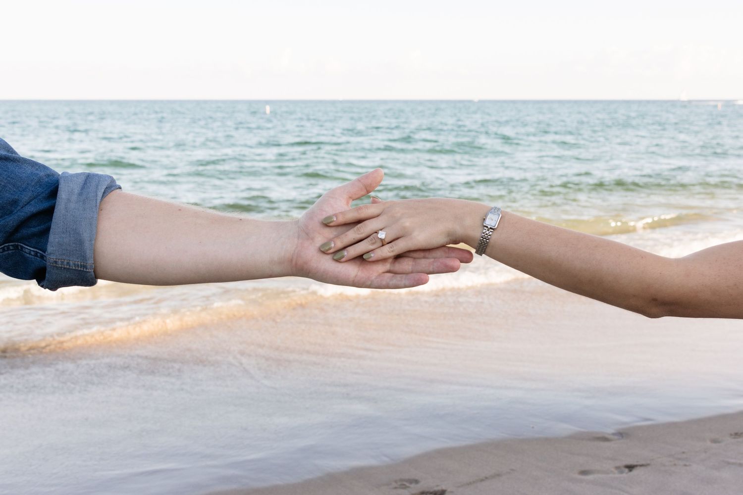 Barefoot couple walking together along the ocean shoreline.