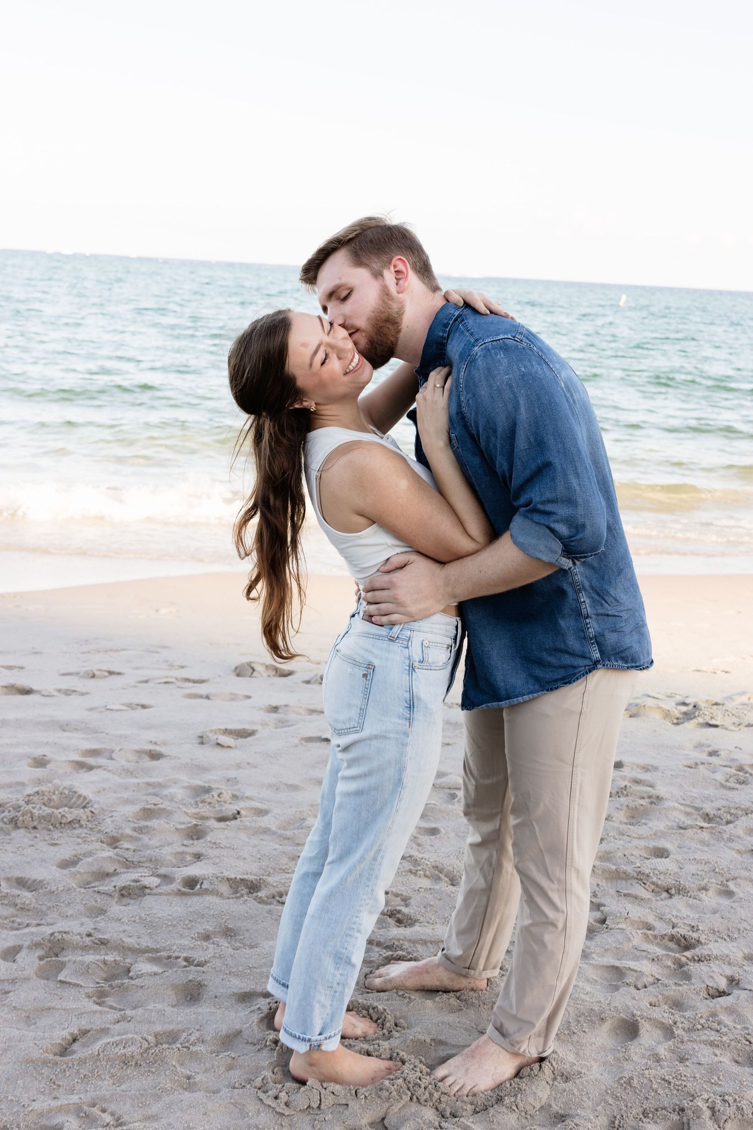 Playful beach embrace captured during sunset photoshoot.