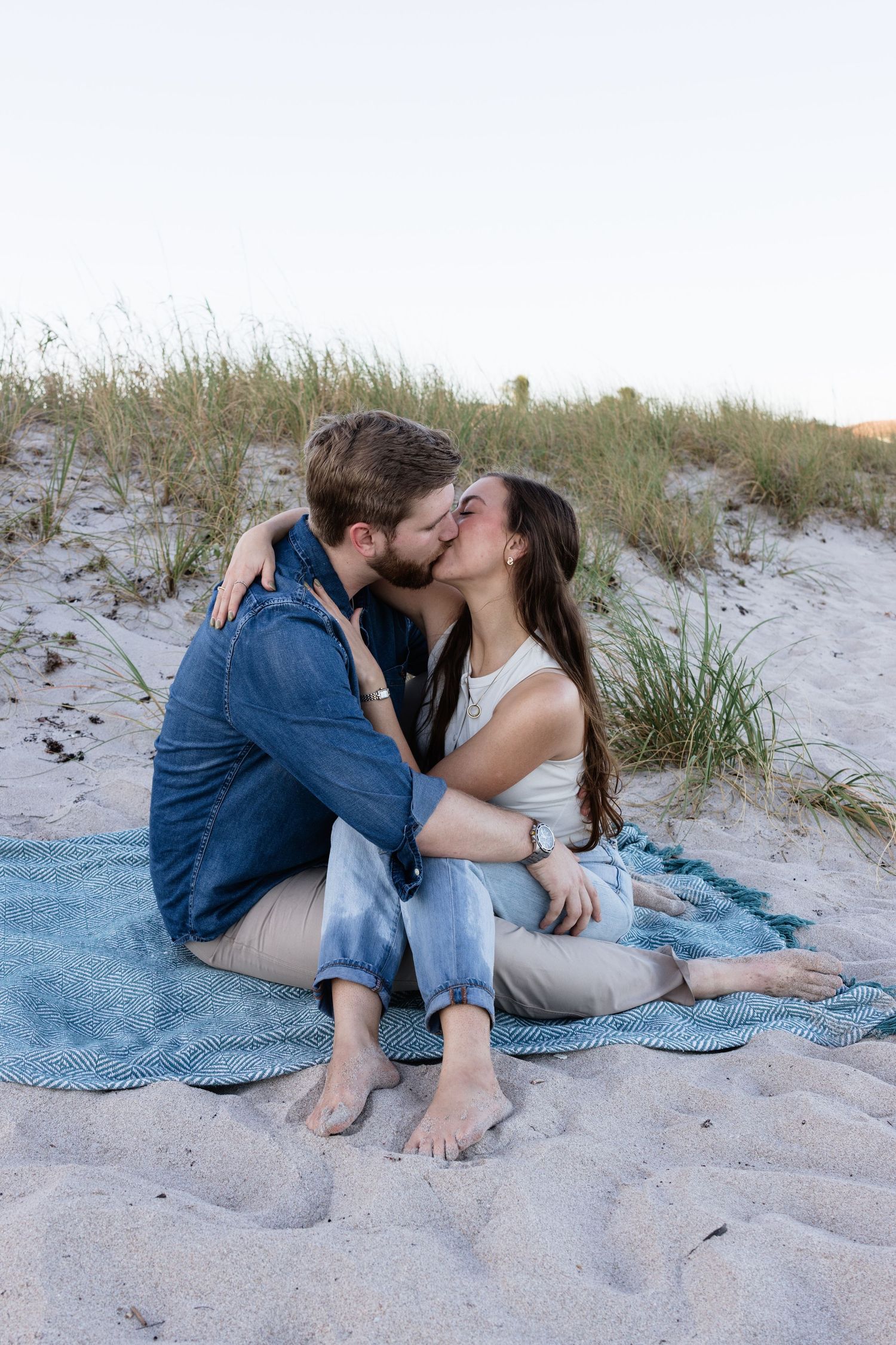 Intimate moment shared between two people on a blue blanket at the beach.