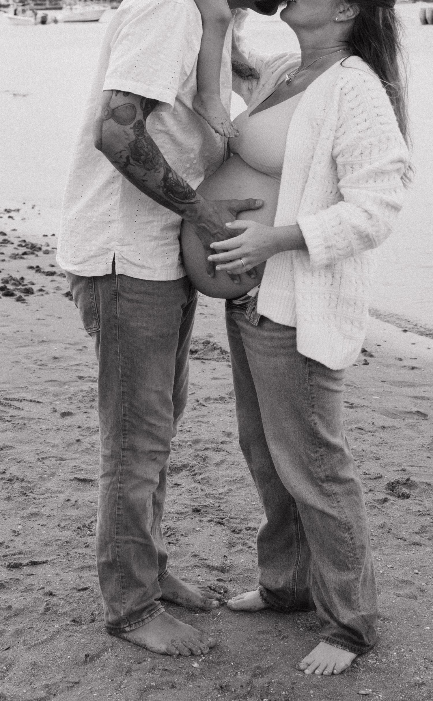 Black and white photo of feet and legs on a sandy beach.