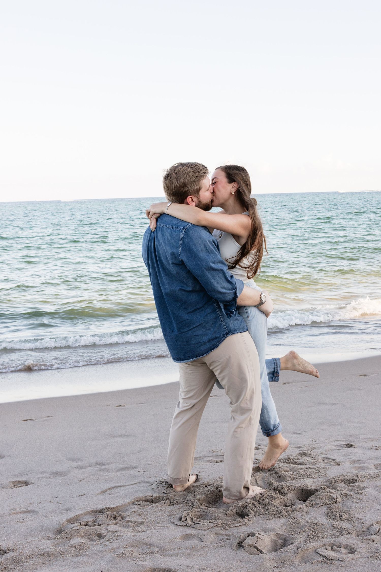 A romantic moment shared between two people on a sandy beach at sunset.