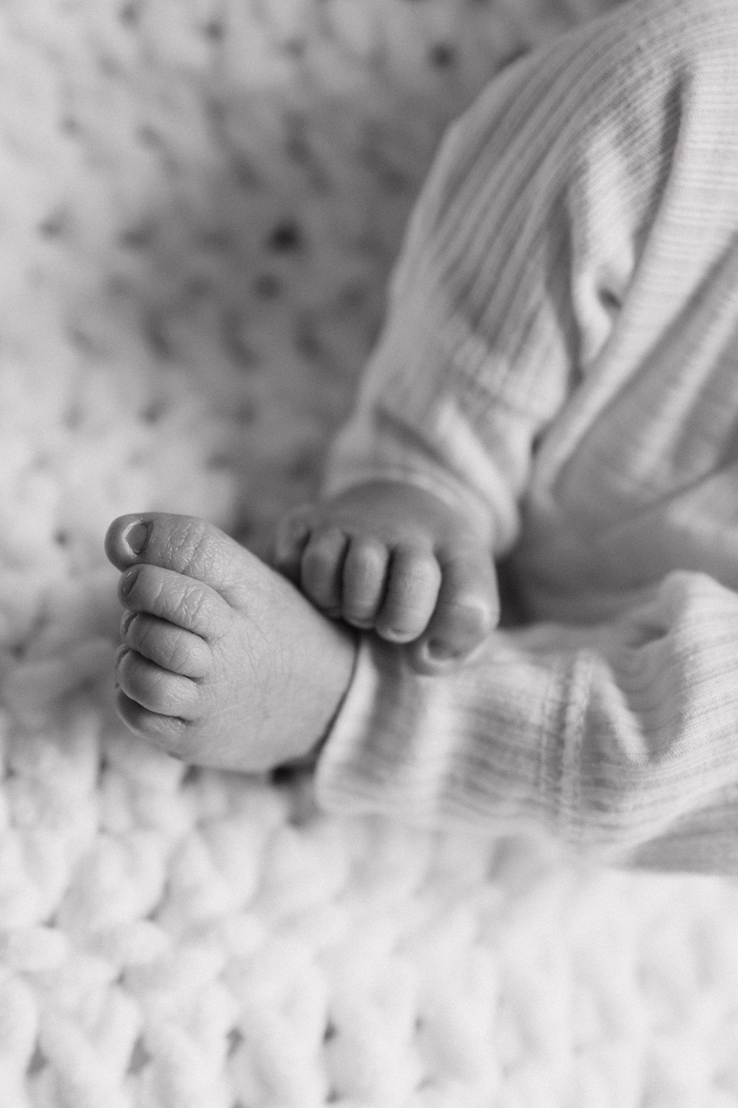 Macro shot of newborn baby toes on soft white blanket.