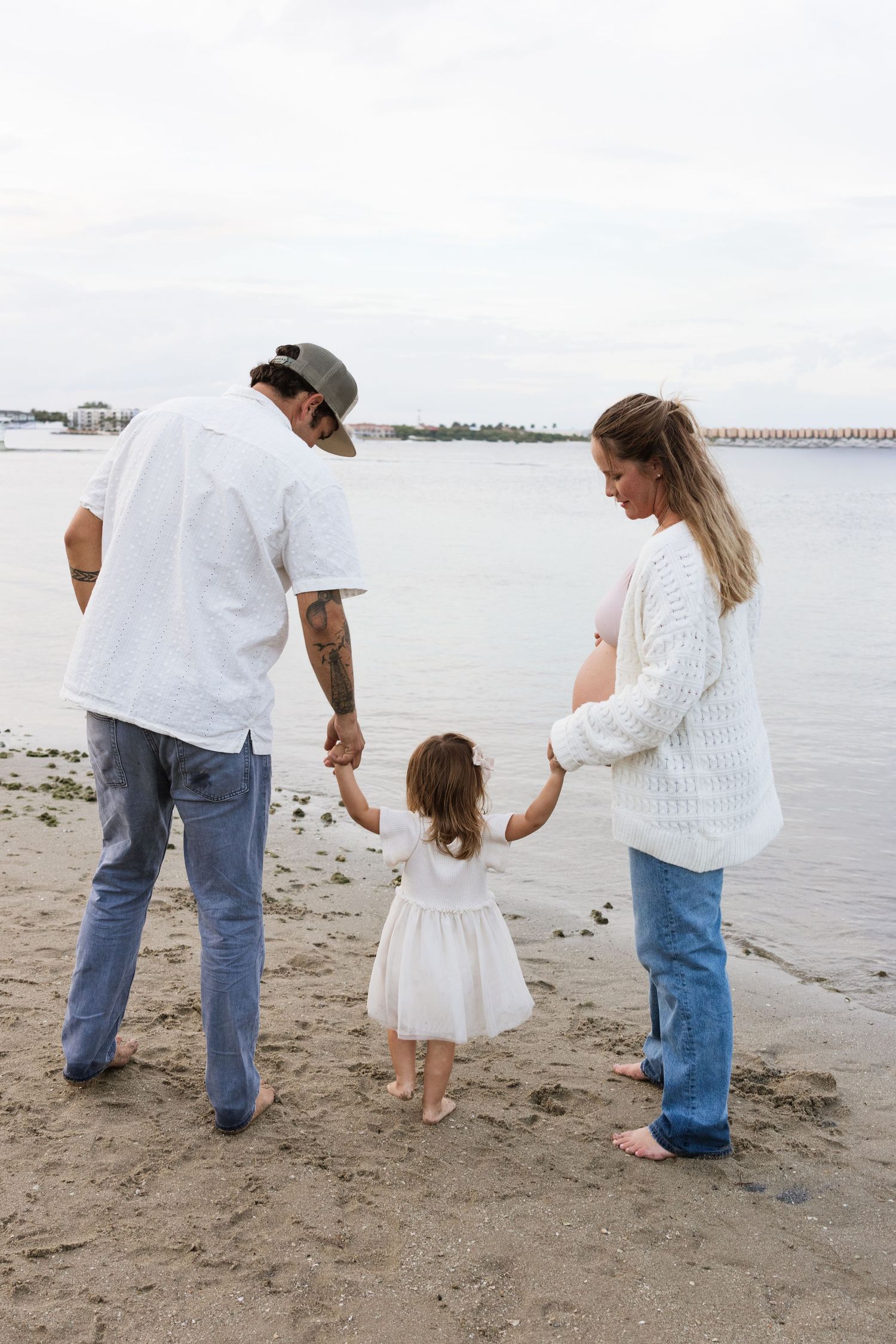 Family strolling along the shoreline collecting seashells together.