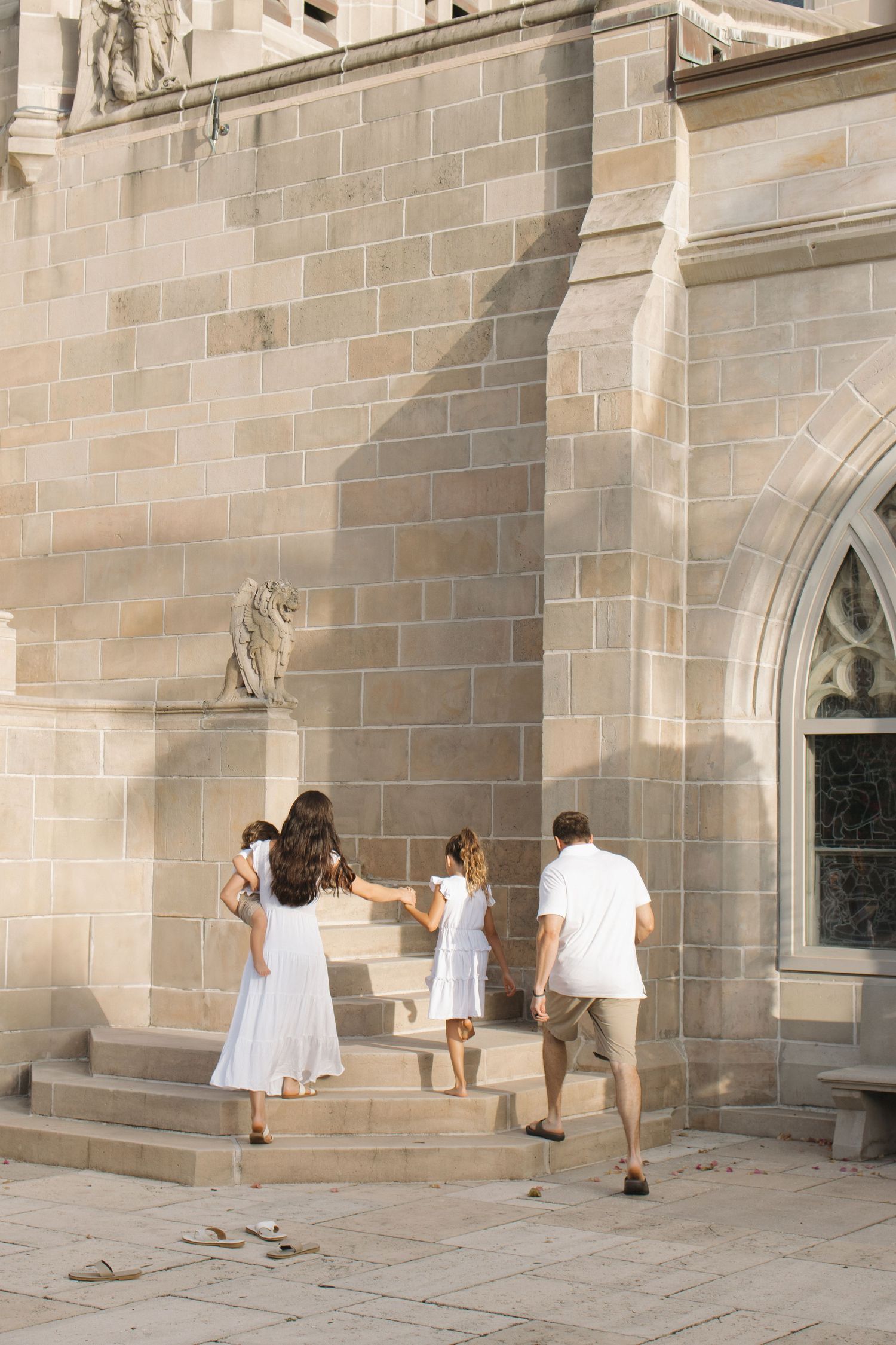 People walking past stone church exterior with gothic architecture.
