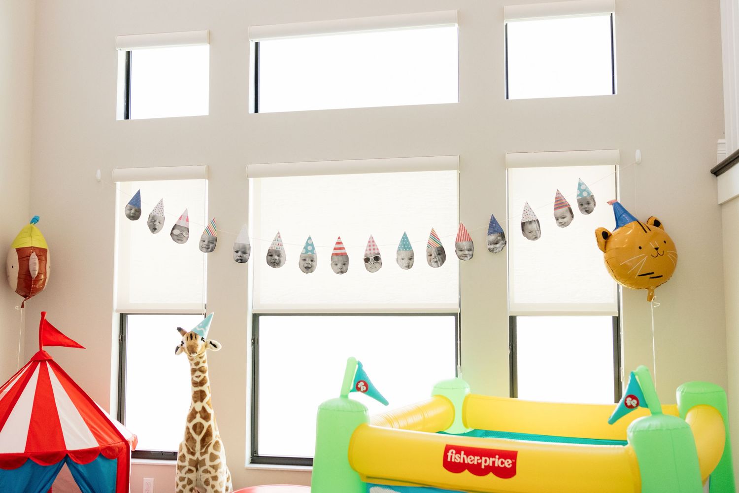 Colorful kids playroom with Fisher-Price toy, giraffe, circus tent, cat balloon, and festive bunting garland near bright windows.
