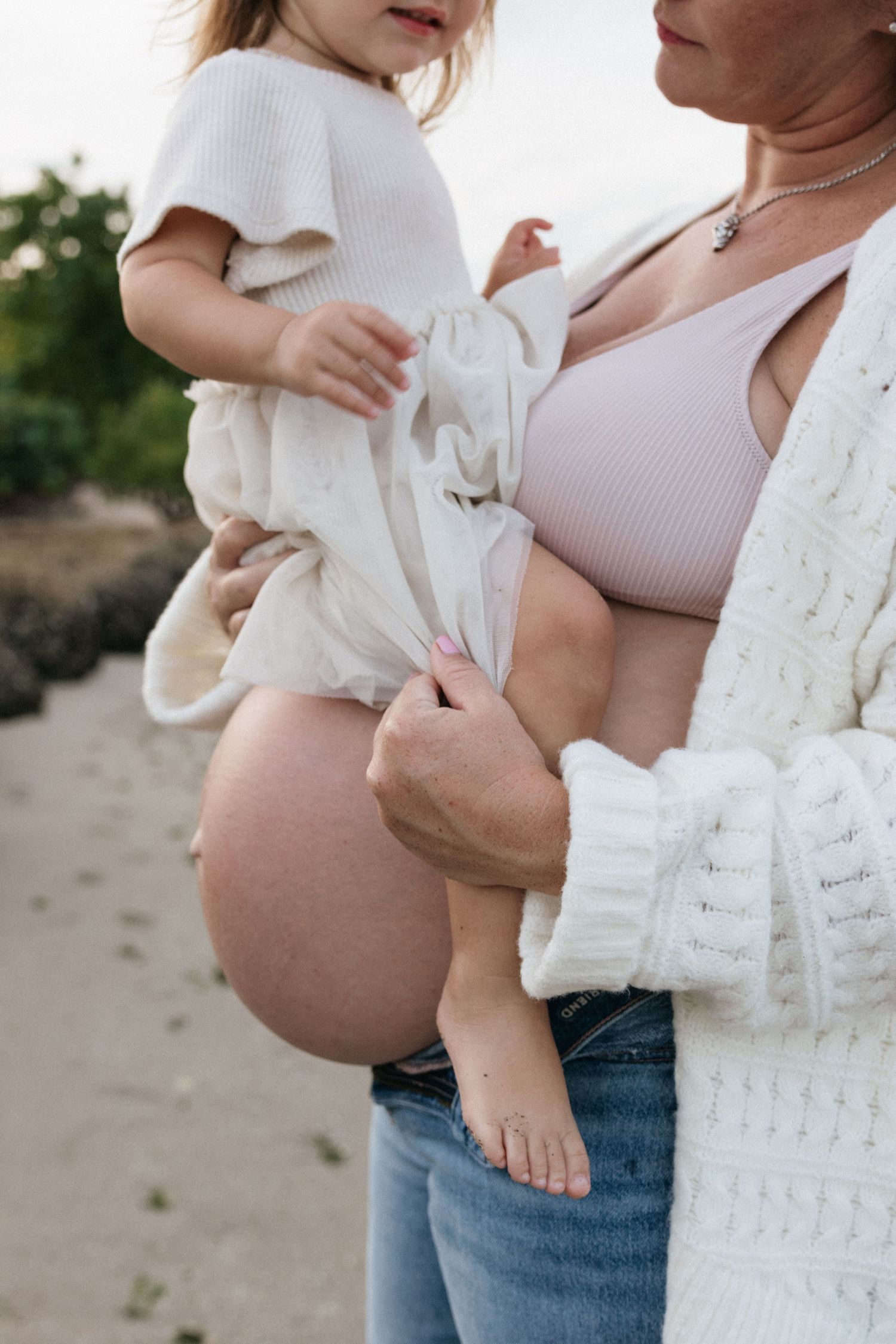 Close-up shots highlighting tender family moments in white clothing on the beach.