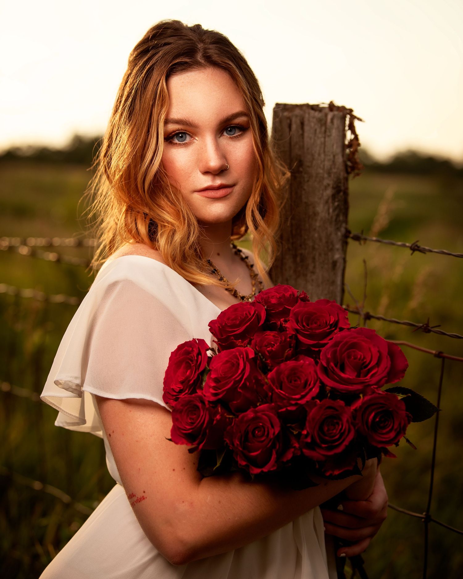 Portrait series with red roses against rustic fence at sunset.