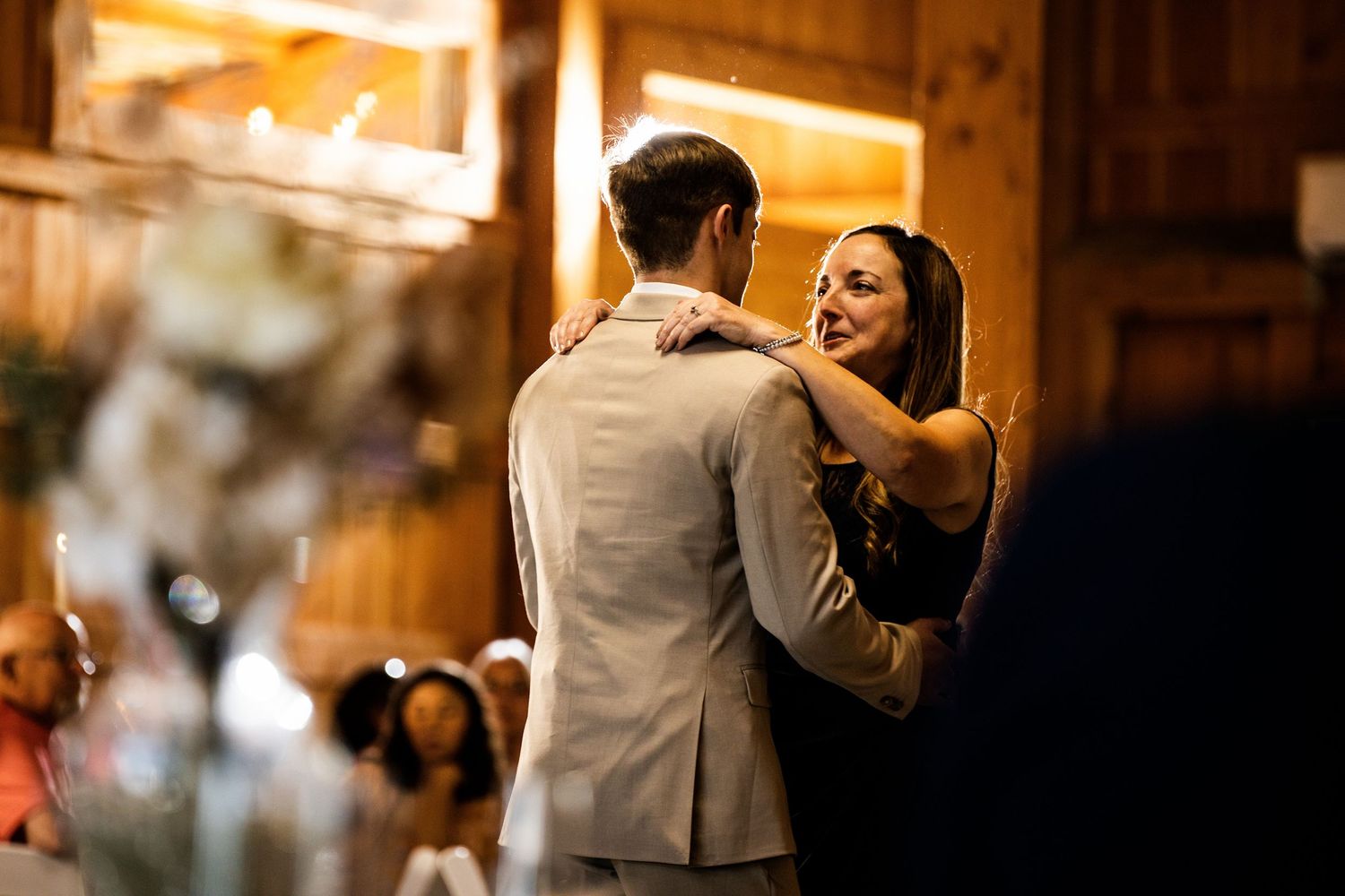 Couple sharing a romantic dance at a rustic barn wedding reception, woman in black dress smiling warmly.