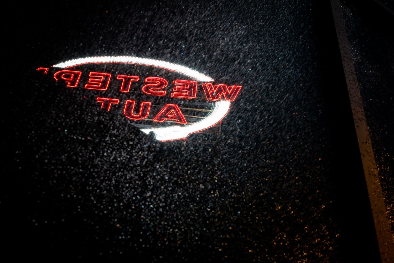 A red neon sign glows against a dark background creating a dramatic illuminated effect.