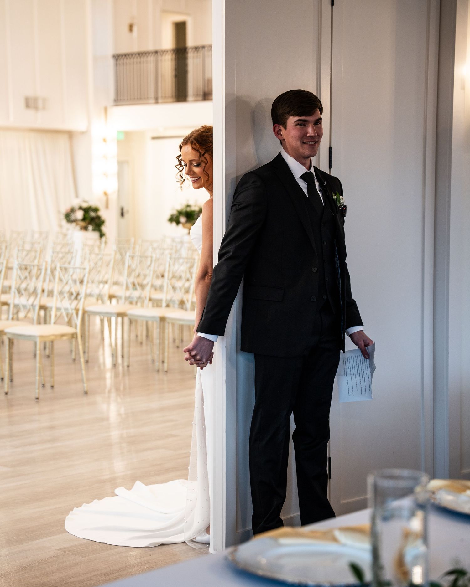 A couple shares a playful first look moment before their wedding ceremony in an elegant white venue.