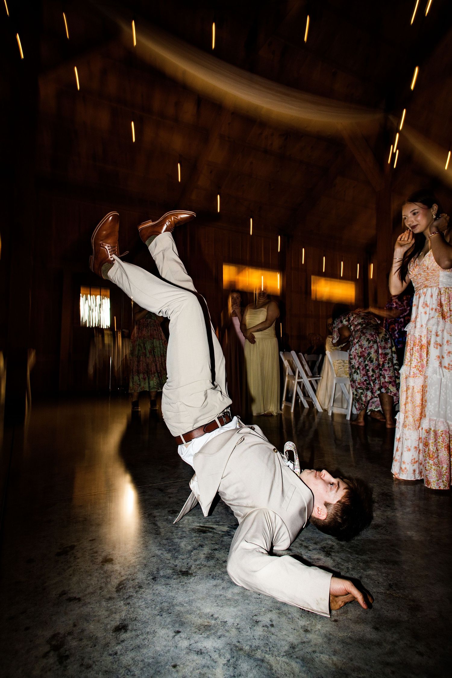 Groom breakdancing on the floor at a lively rustic barn wedding reception.