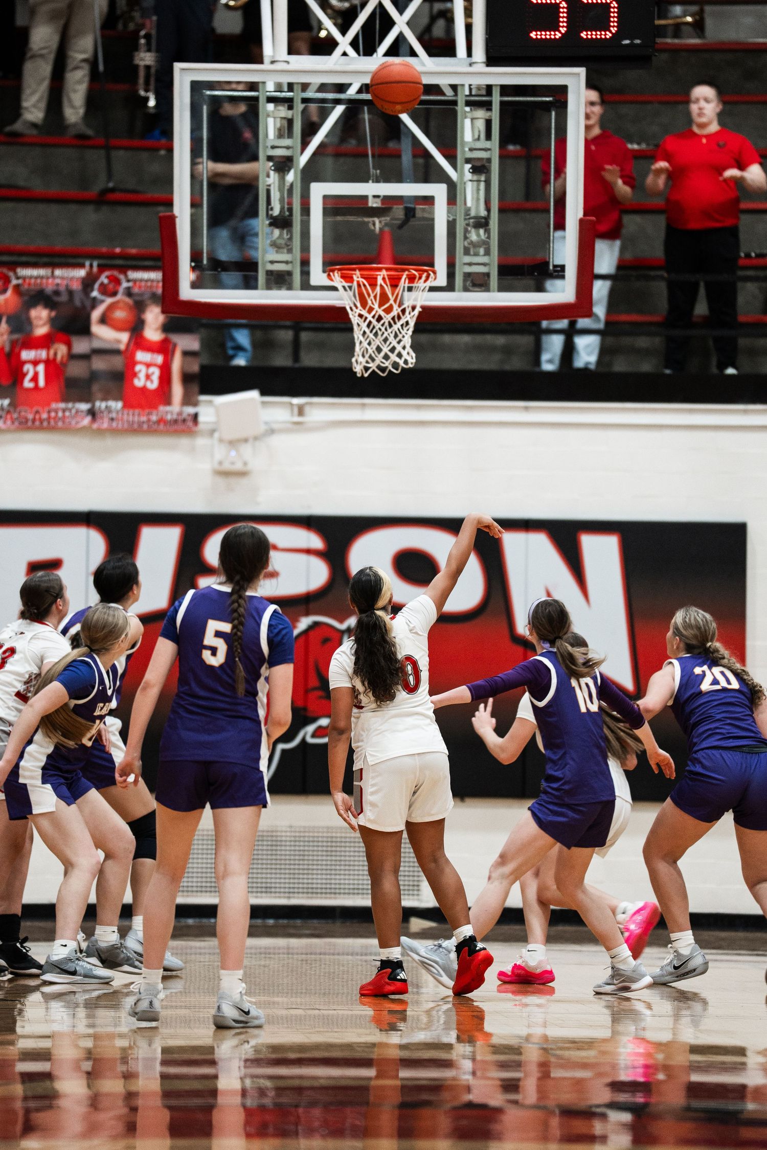 Basketball players from opposing teams line up on court during free throw attempt.