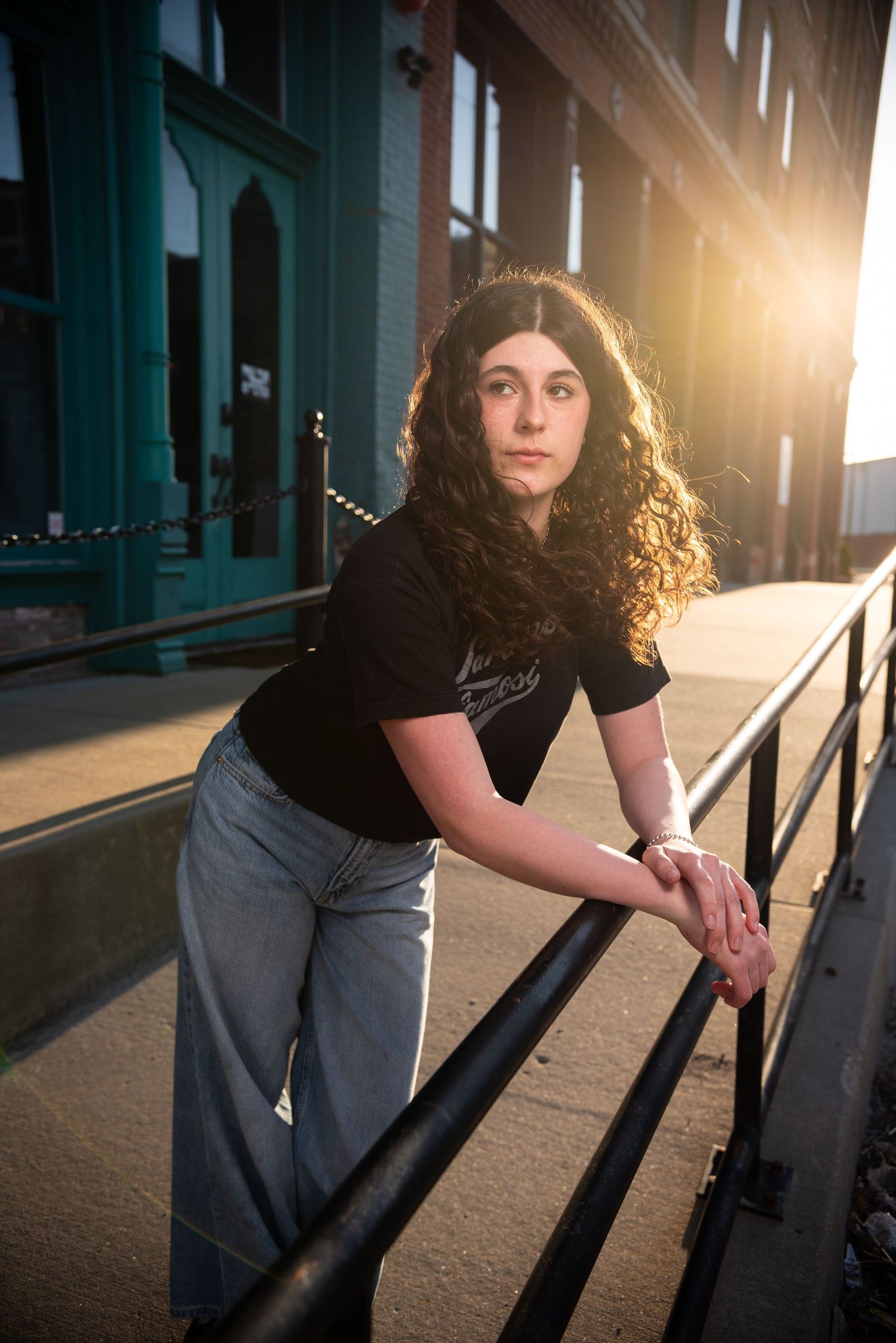 Dramatic backlit portrait in industrial setting with strong shadows.