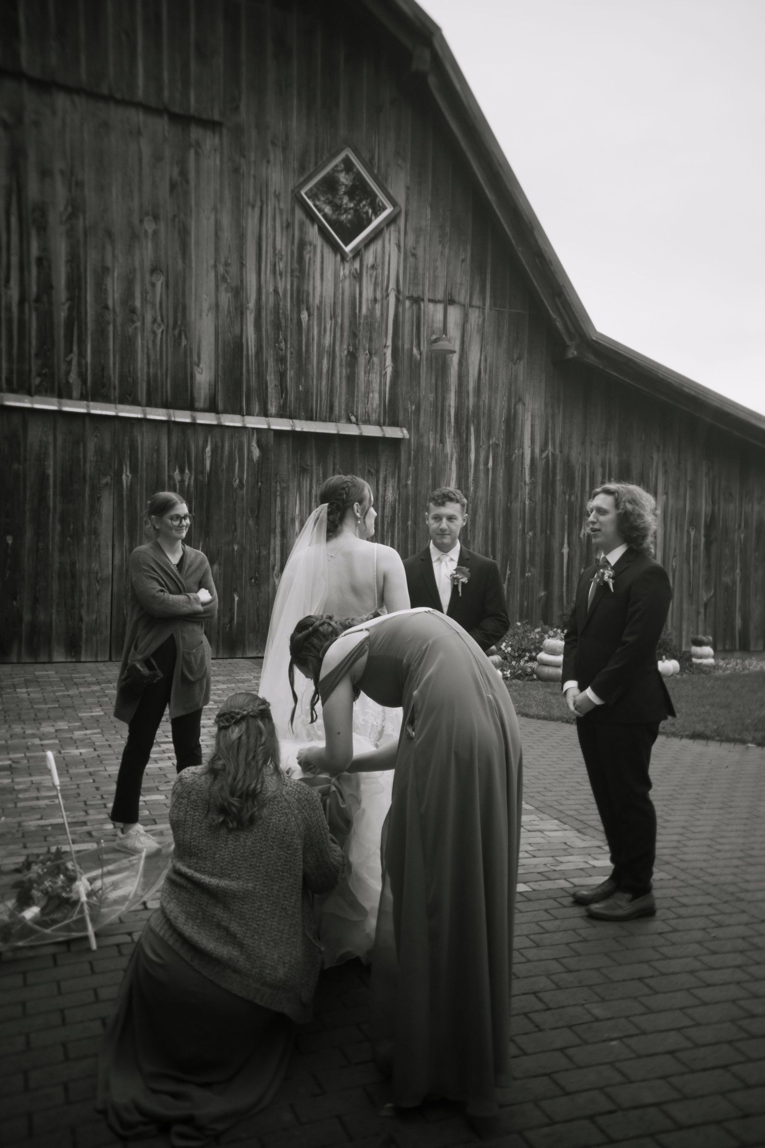 A sequence of black and white photos showing people interacting in front of a rustic wooden barn.