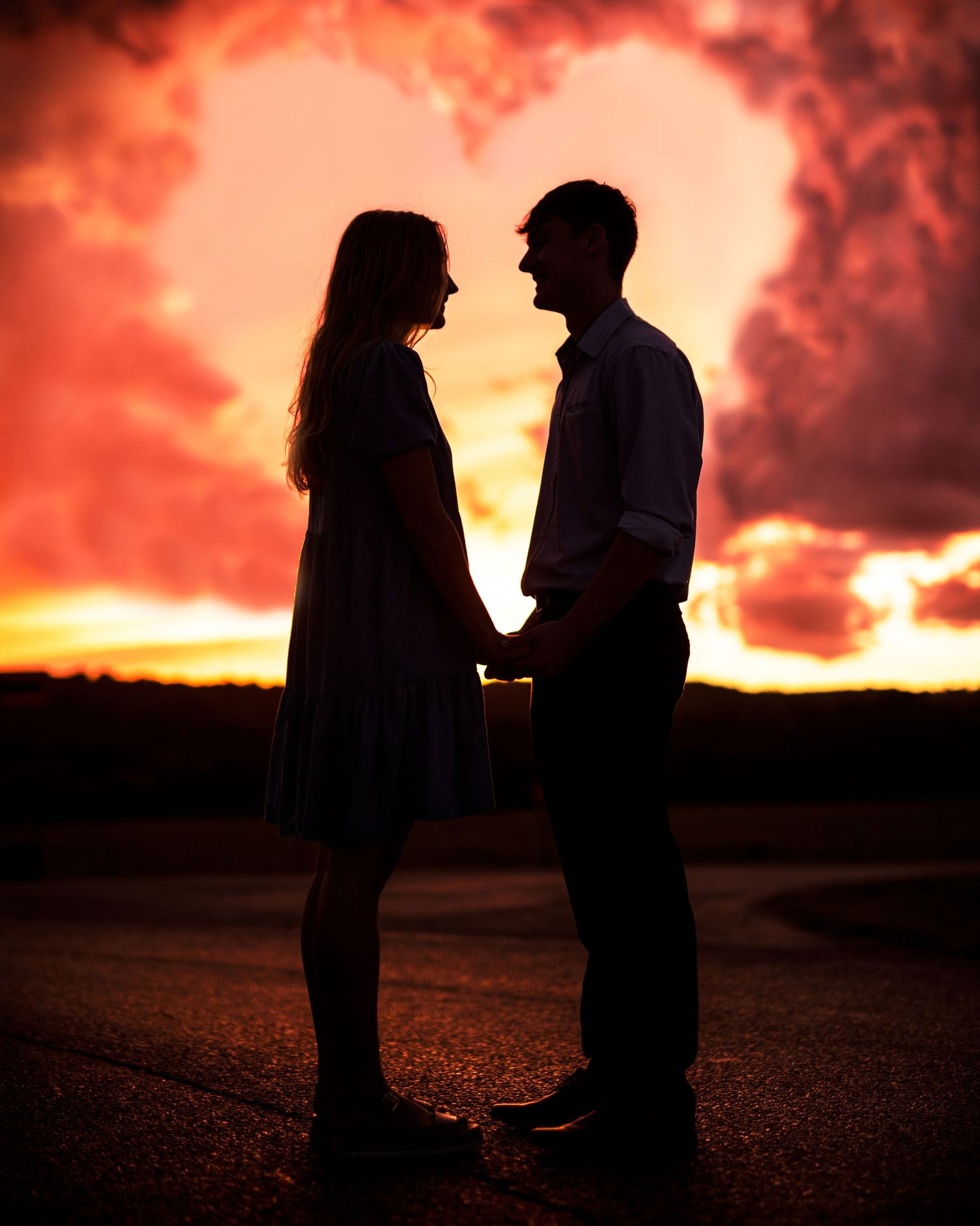 Silhouettes of people standing together against a dramatic red and orange sunset sky.