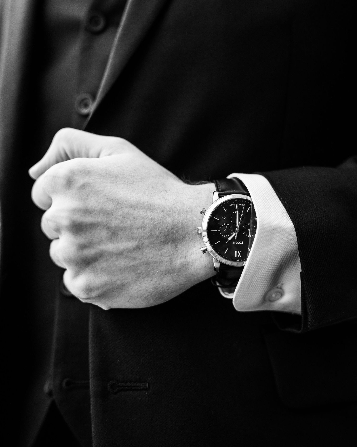 A black and white photo series showing a wrist wearing an elegant round watch from different angles.