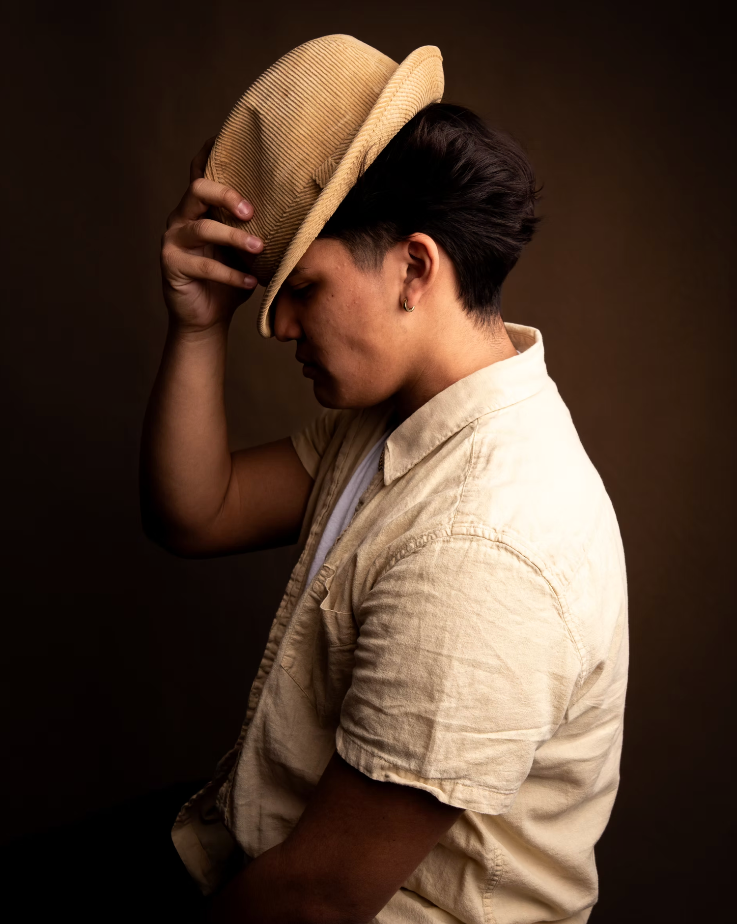 Artistic portrait series showing person in beige shirt and cowboy hat against dark background.