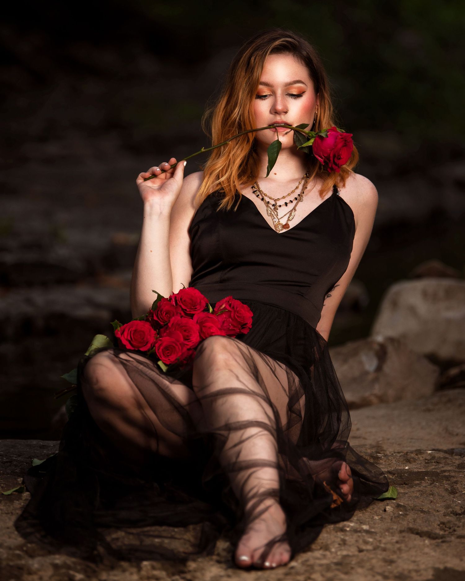 Artistic portrait with red roses in dark moody lighting.