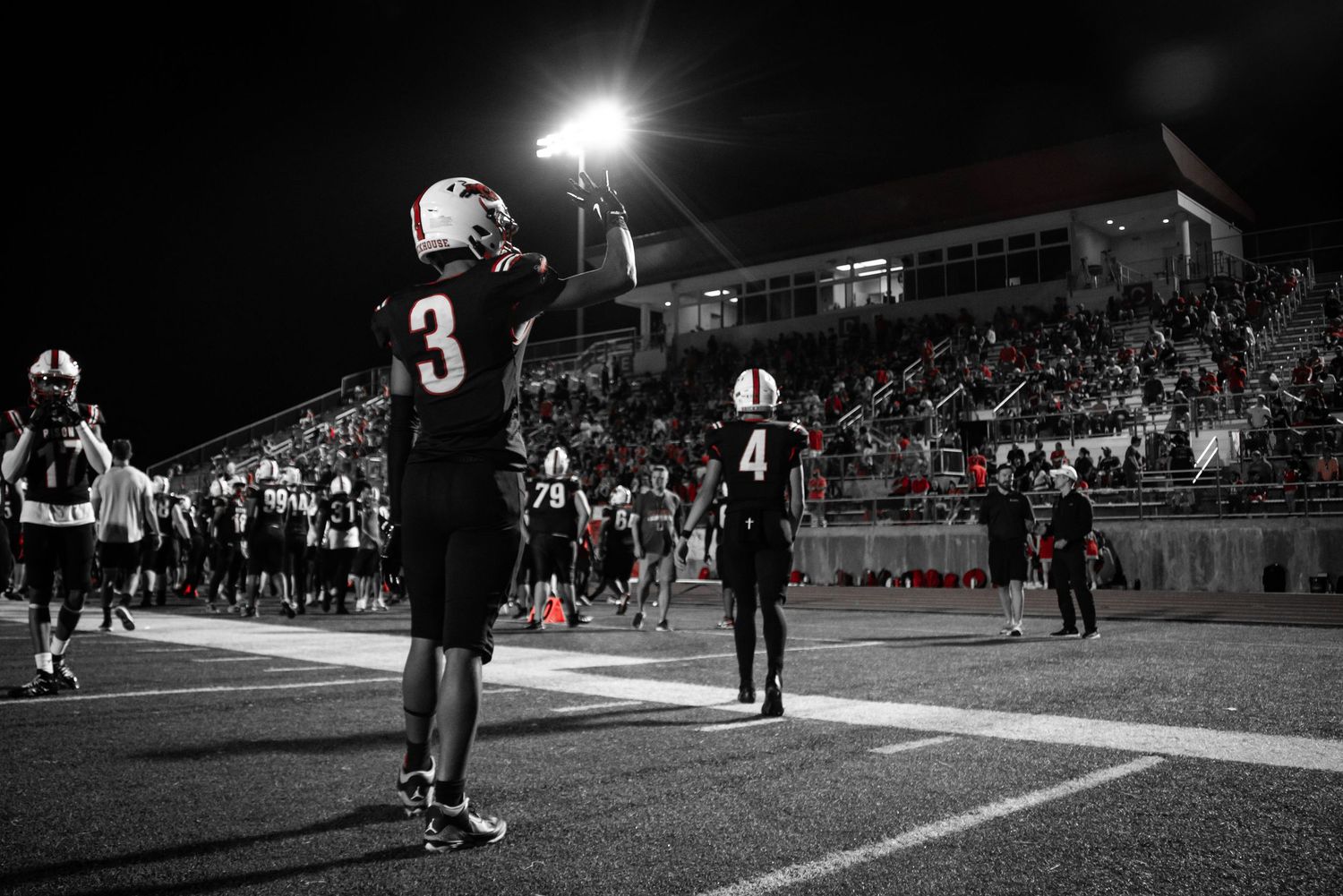 Black and white sports action shot under stadium lights at night.