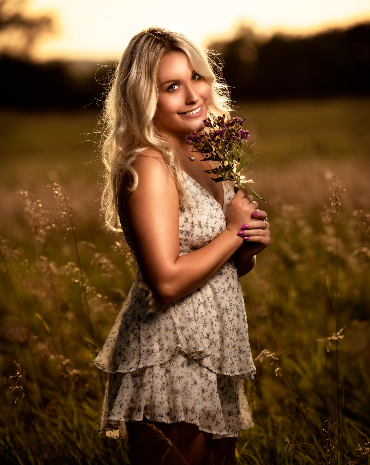 Young girl holding wildflowers in sunset-lit meadow.