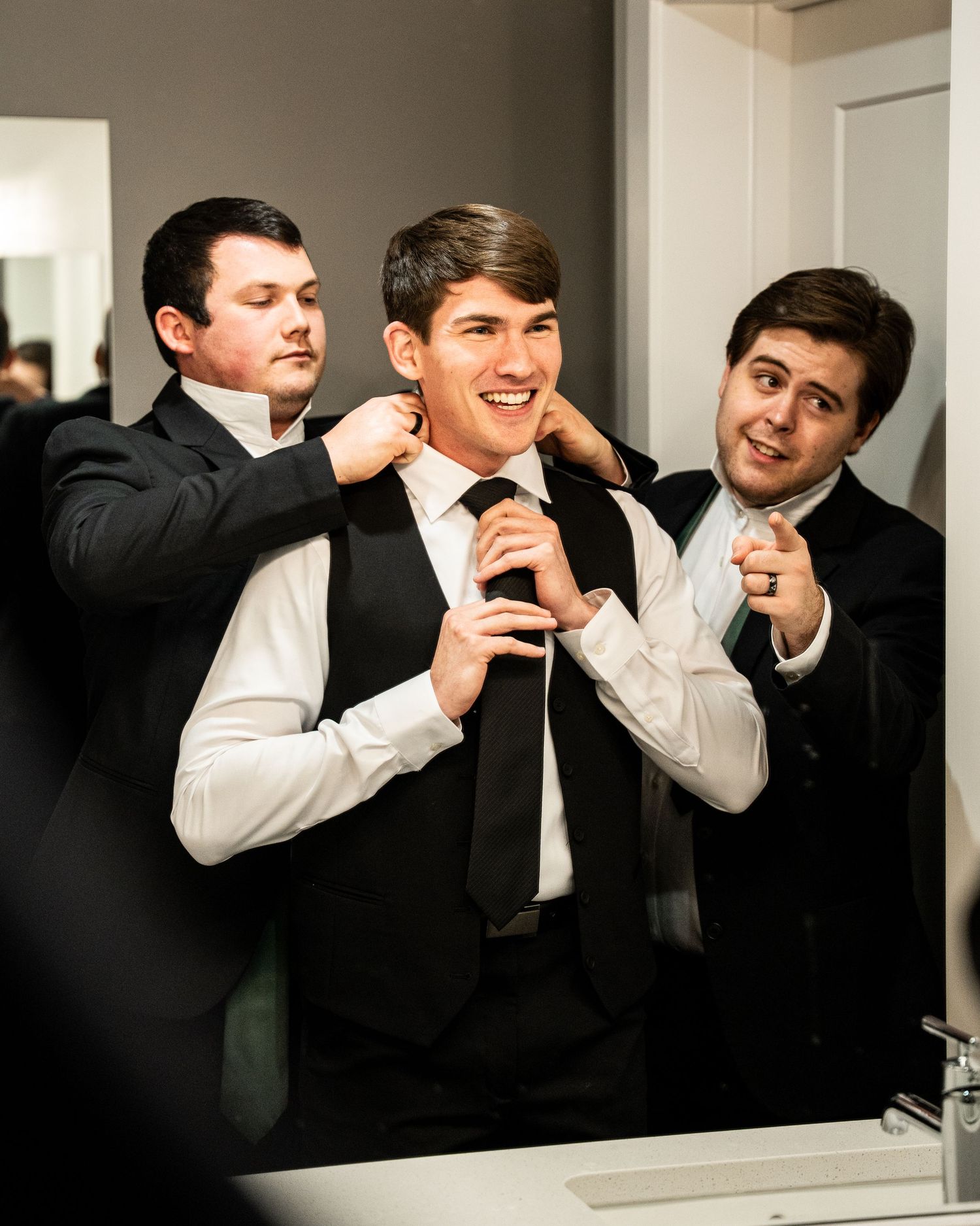 Four sequential photos show groomsmen playfully adjusting their ties and laughing together in formal attire.