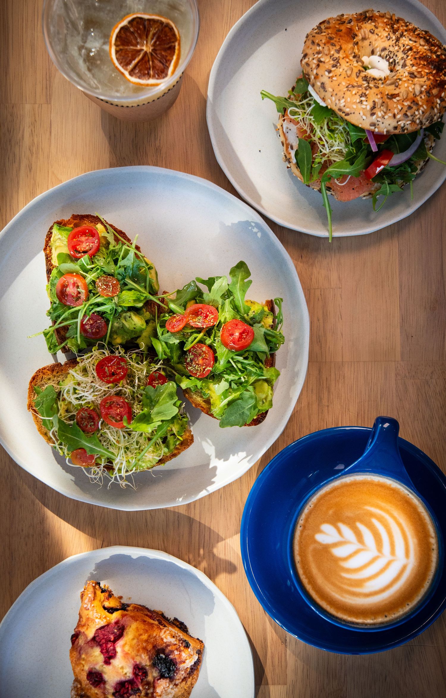 Artfully plated cafe dishes including sandwiches and latte art on wooden tables with natural lighting.