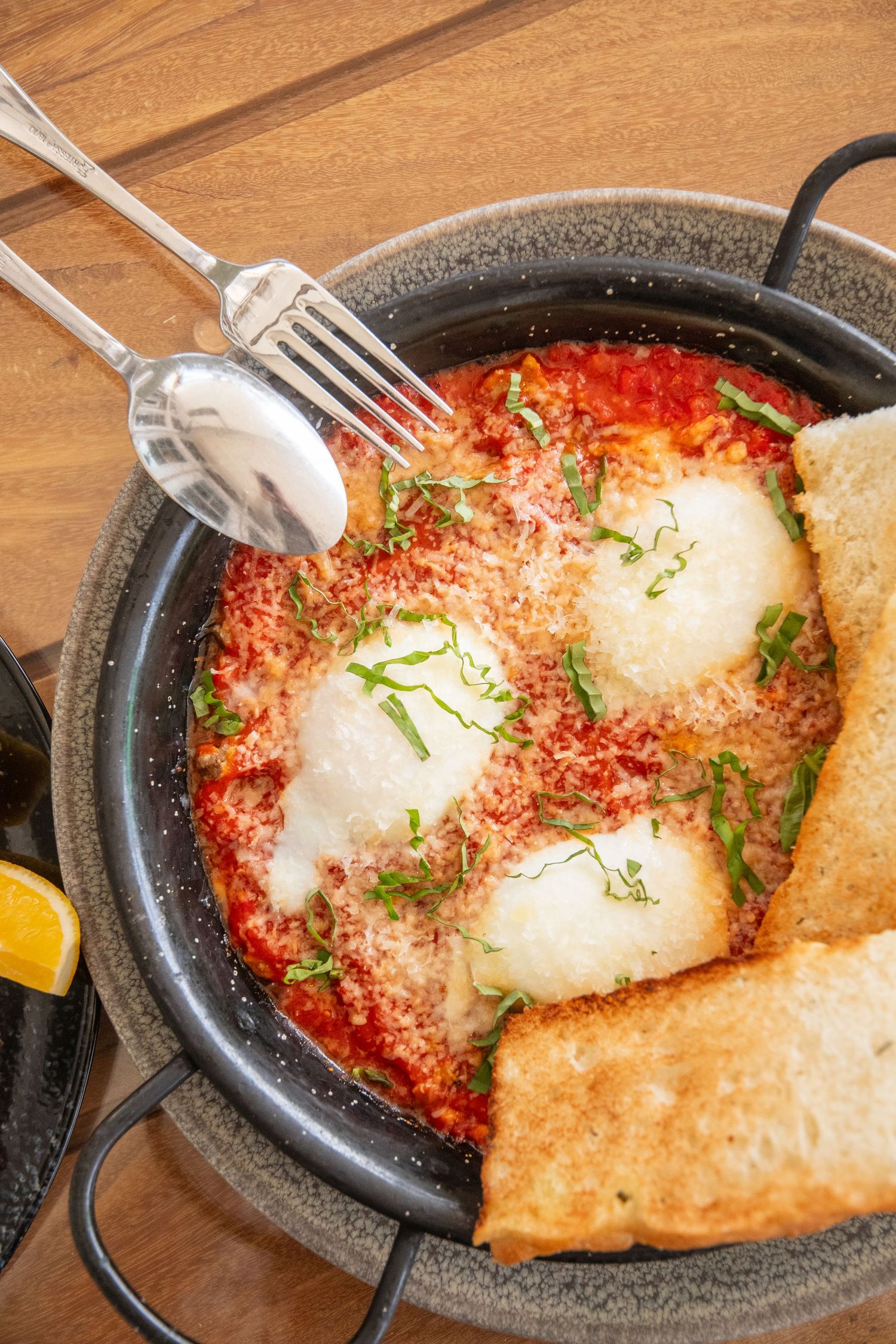Close-up of shakshuka with poached eggs in spicy tomato sauce served with crusty bread.
