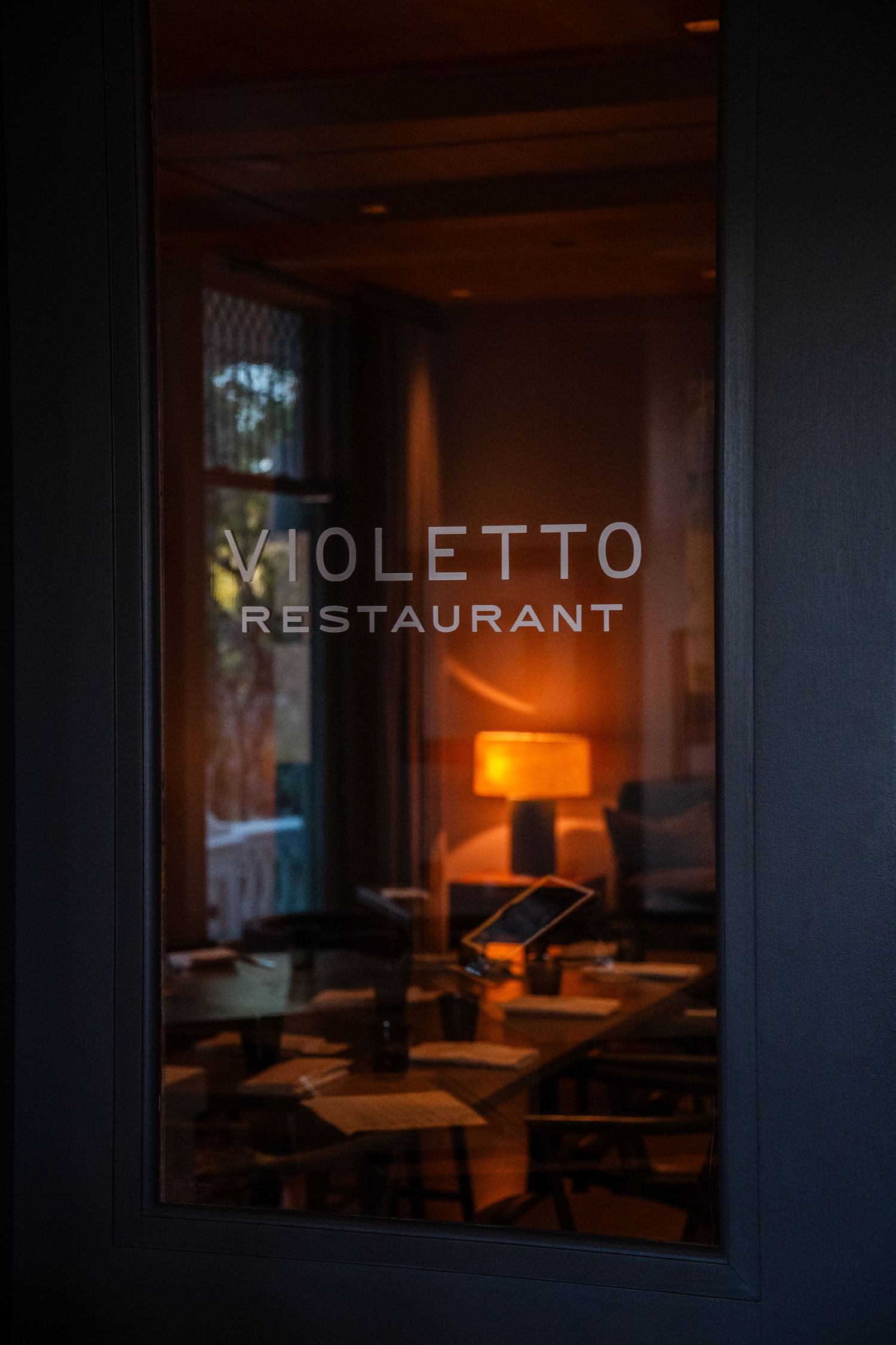 Exterior view of Violetto restaurant signage illuminated in the evening with a modern storefront design.