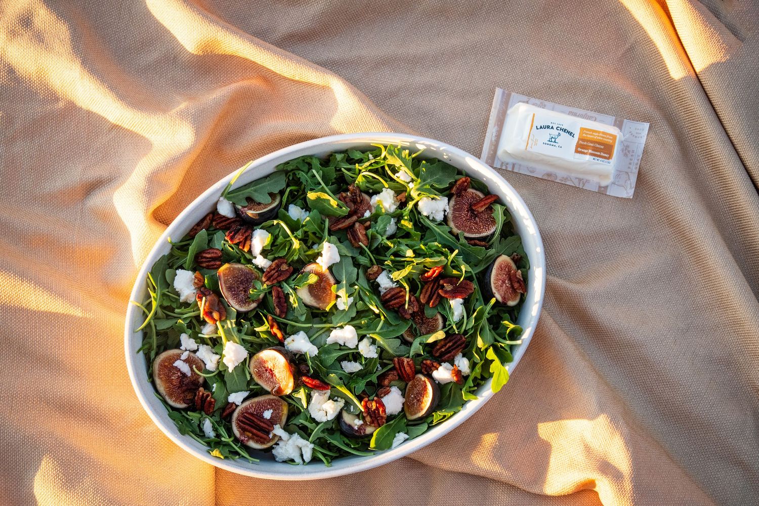Gourmet salad with mixed greens and toppings served on a white oval plate.