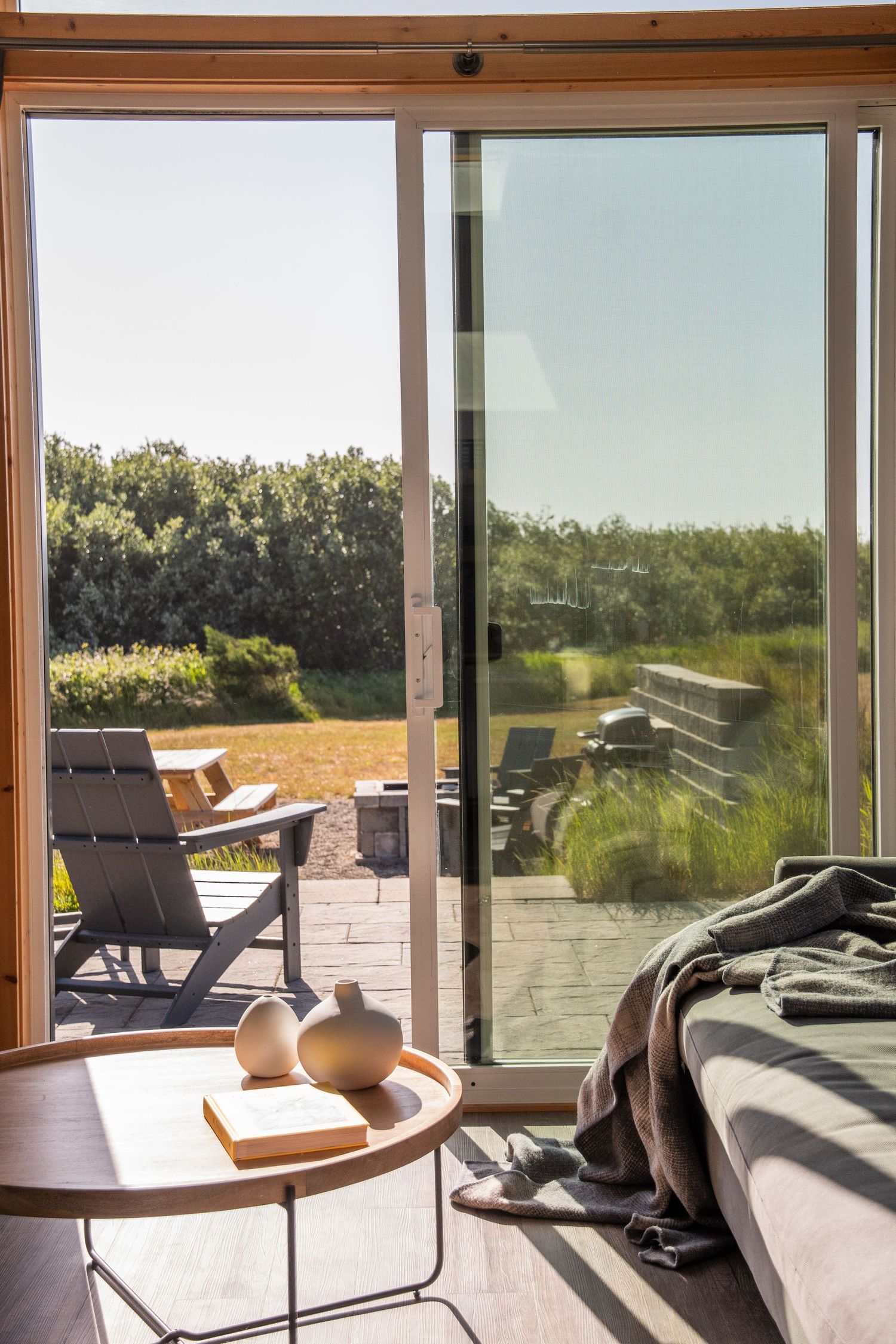 Modern beach house interior with floor-to-ceiling windows and outdoor deck furniture.