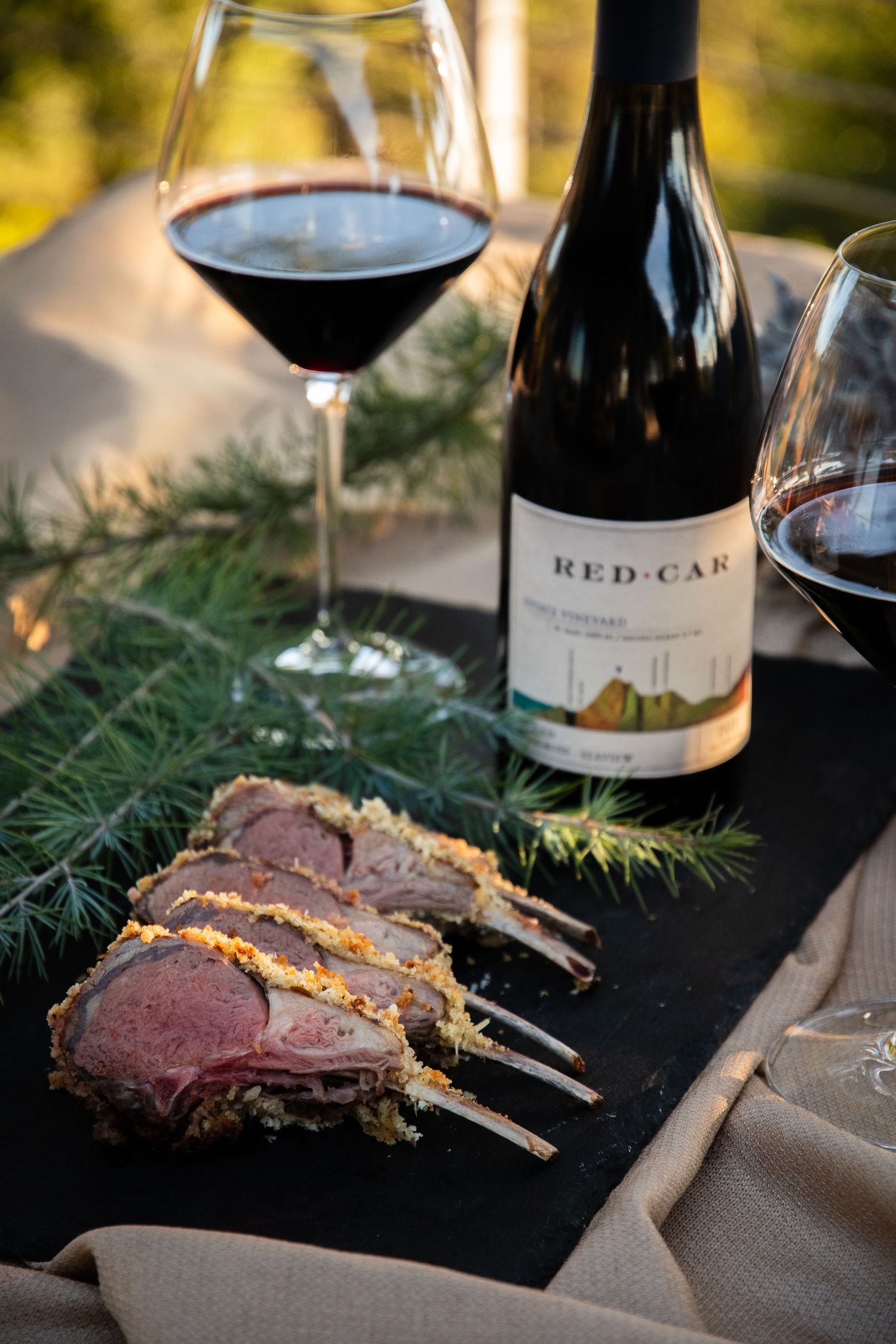 Perfectly cooked prime rib steaks served with red wine in an outdoor dining setting.