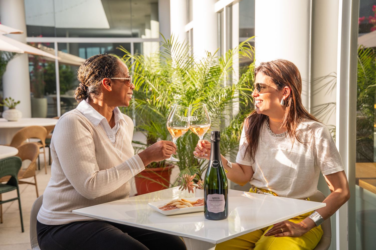 Two people enjoying wine and conversation at outdoor cafe table.