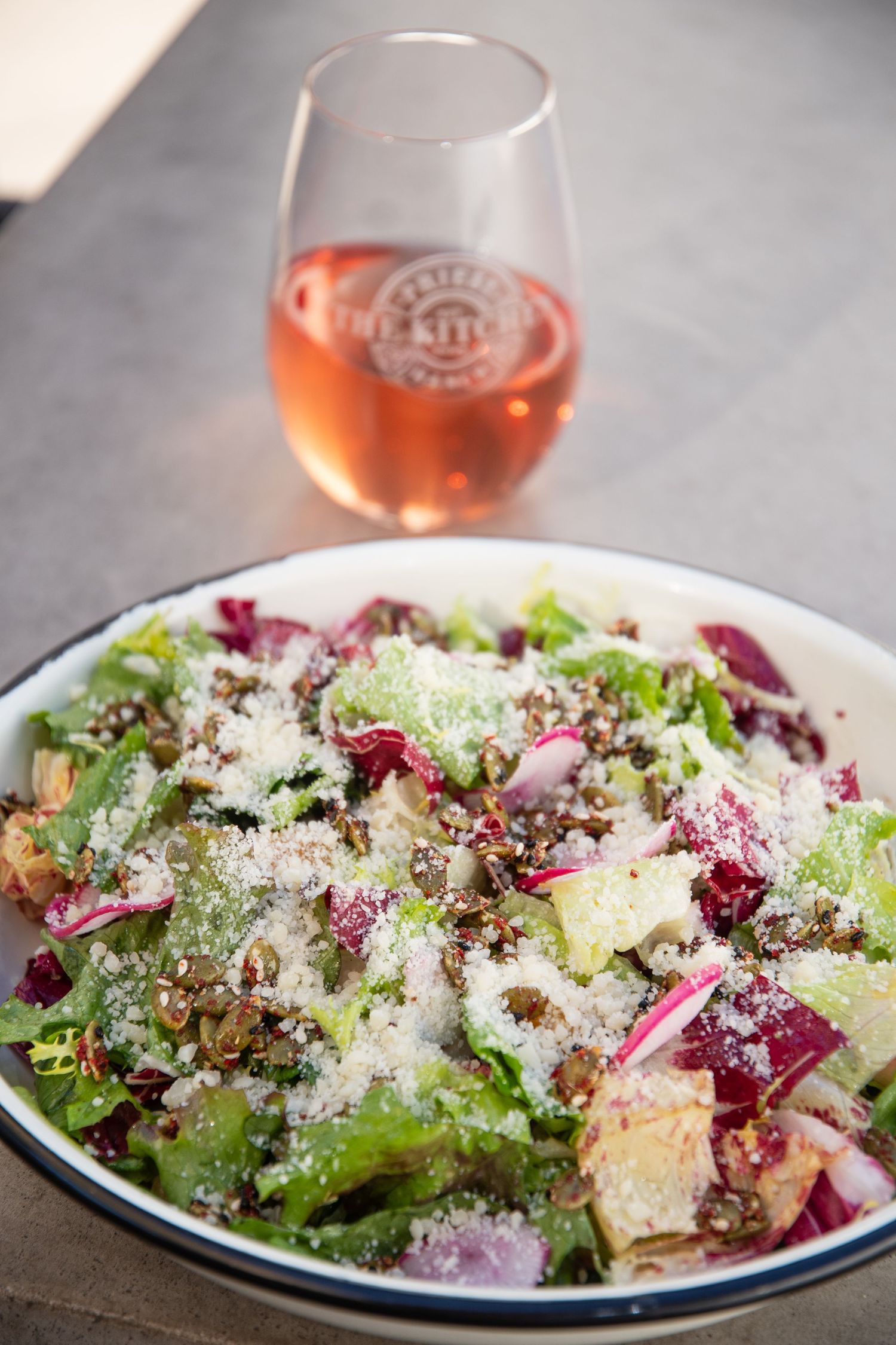 Fresh salad with shaved cheese, red onions and mixed greens served in a bistro-style bowl.