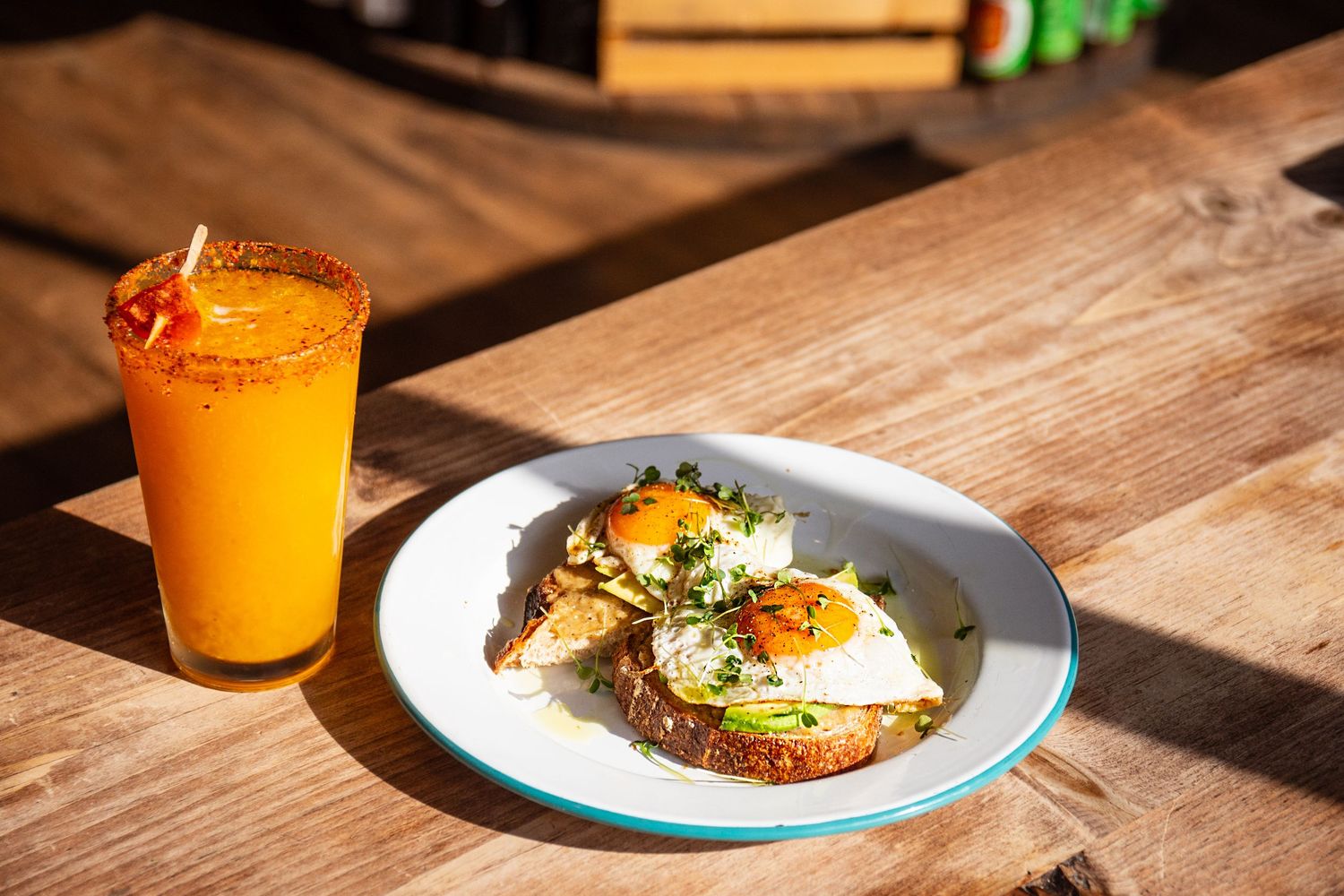 Breakfast plates with eggs and orange juice on a rustic wooden table in morning light.