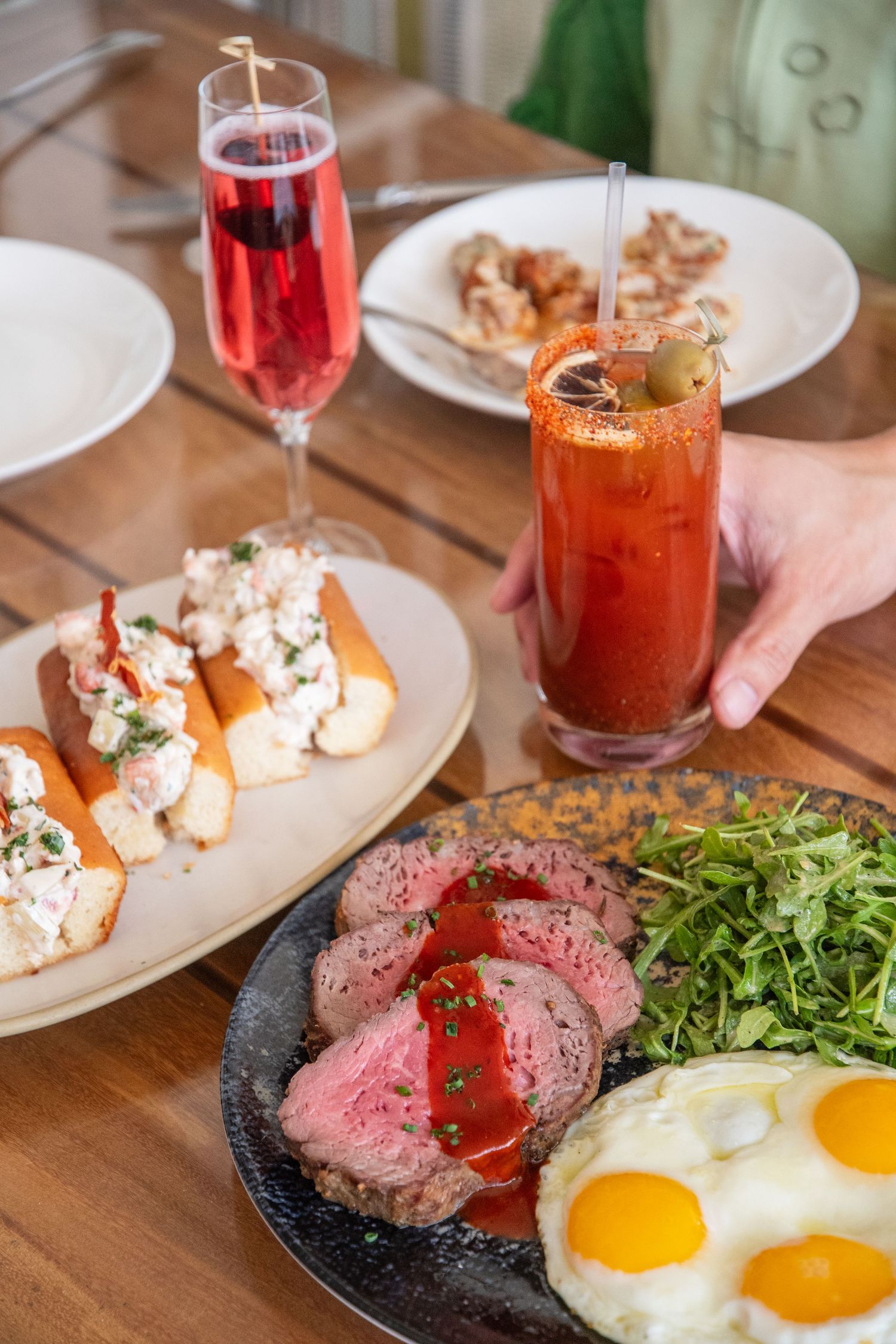 Steak and eggs dish with arugula salad and bloody mary cocktail on a cast iron plate.