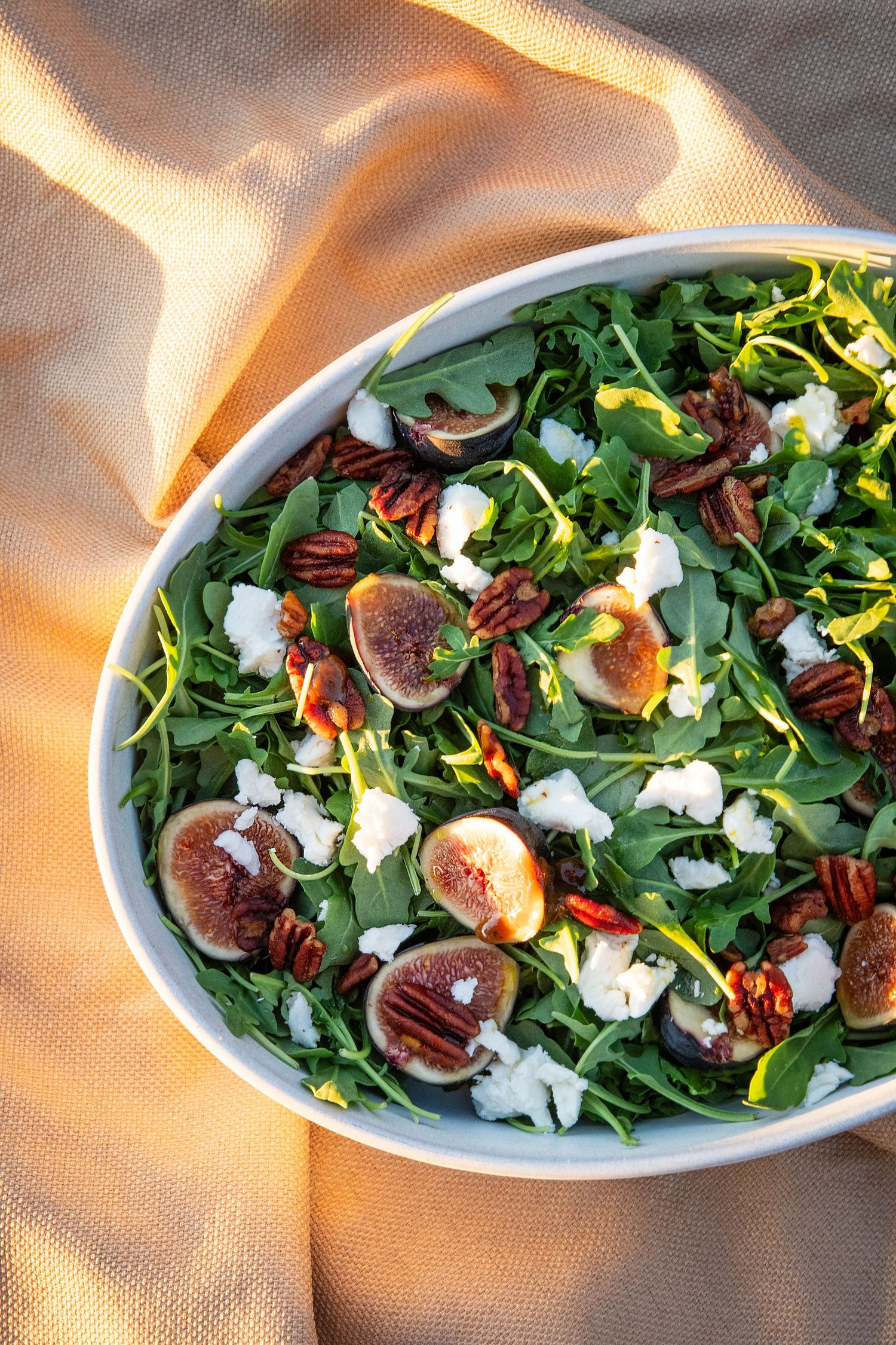 Elegant salad featuring fresh figs, nuts, and cheese arranged on crisp greens.