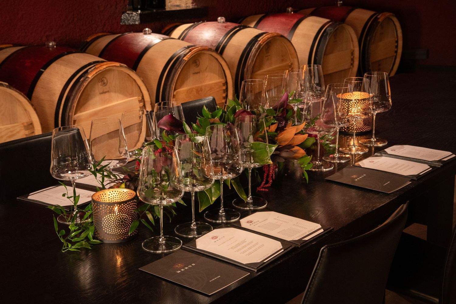 Elegant wine tasting setup with barrels and glassware in a dimly lit room.