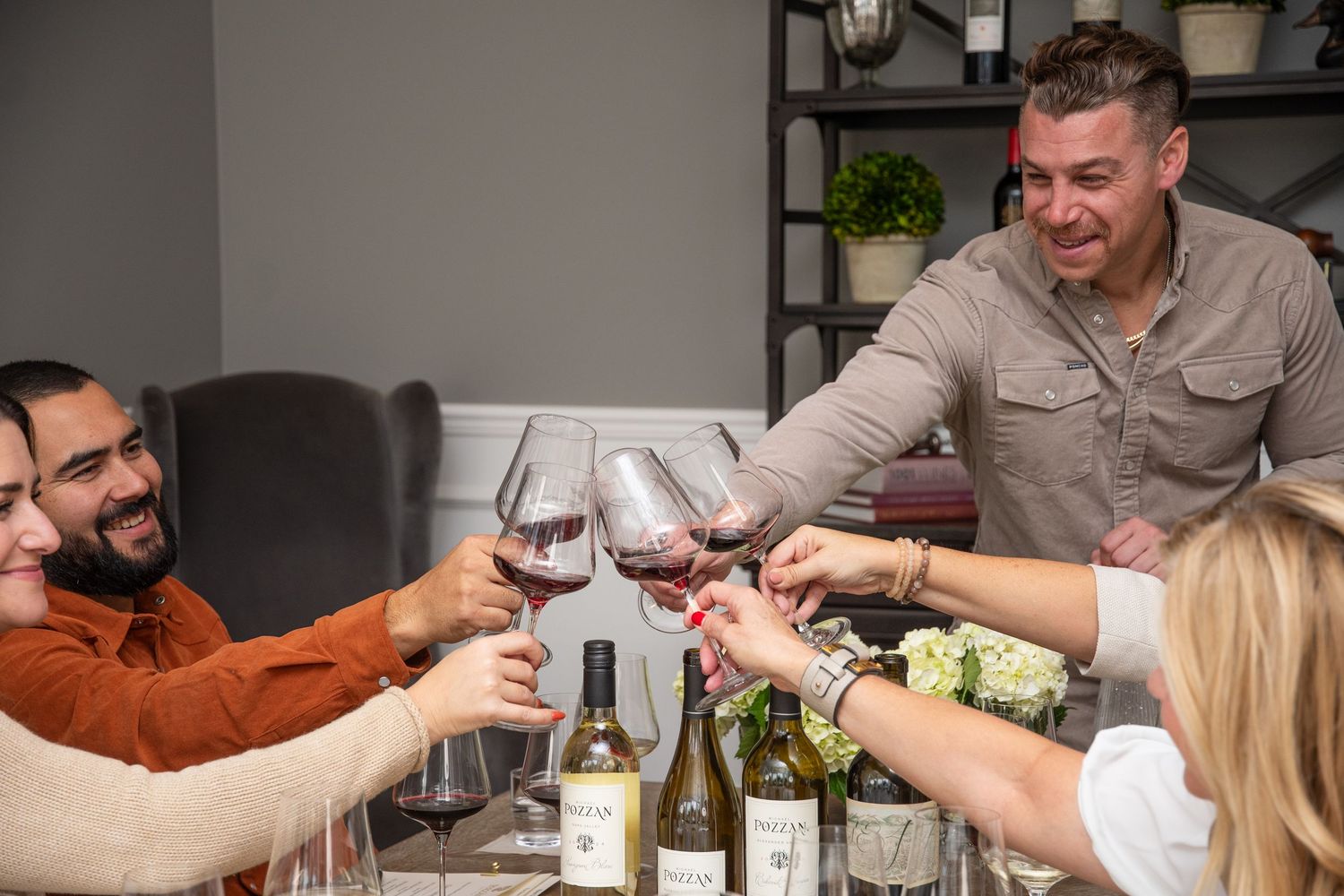 Group toasting with wine glasses around a dining table during a social gathering.