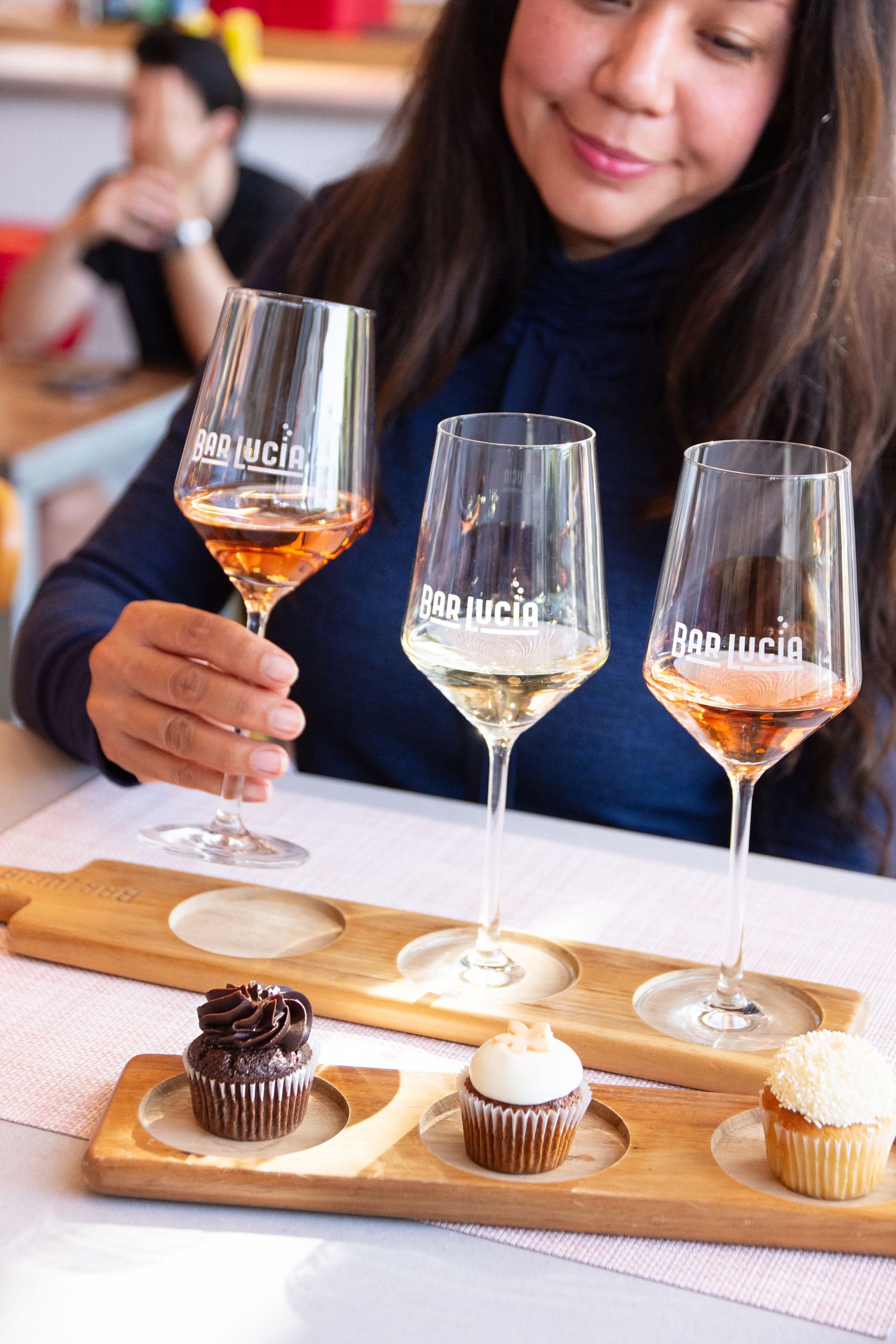 Wine tasting flight with three glasses and paired cupcakes on wooden boards.