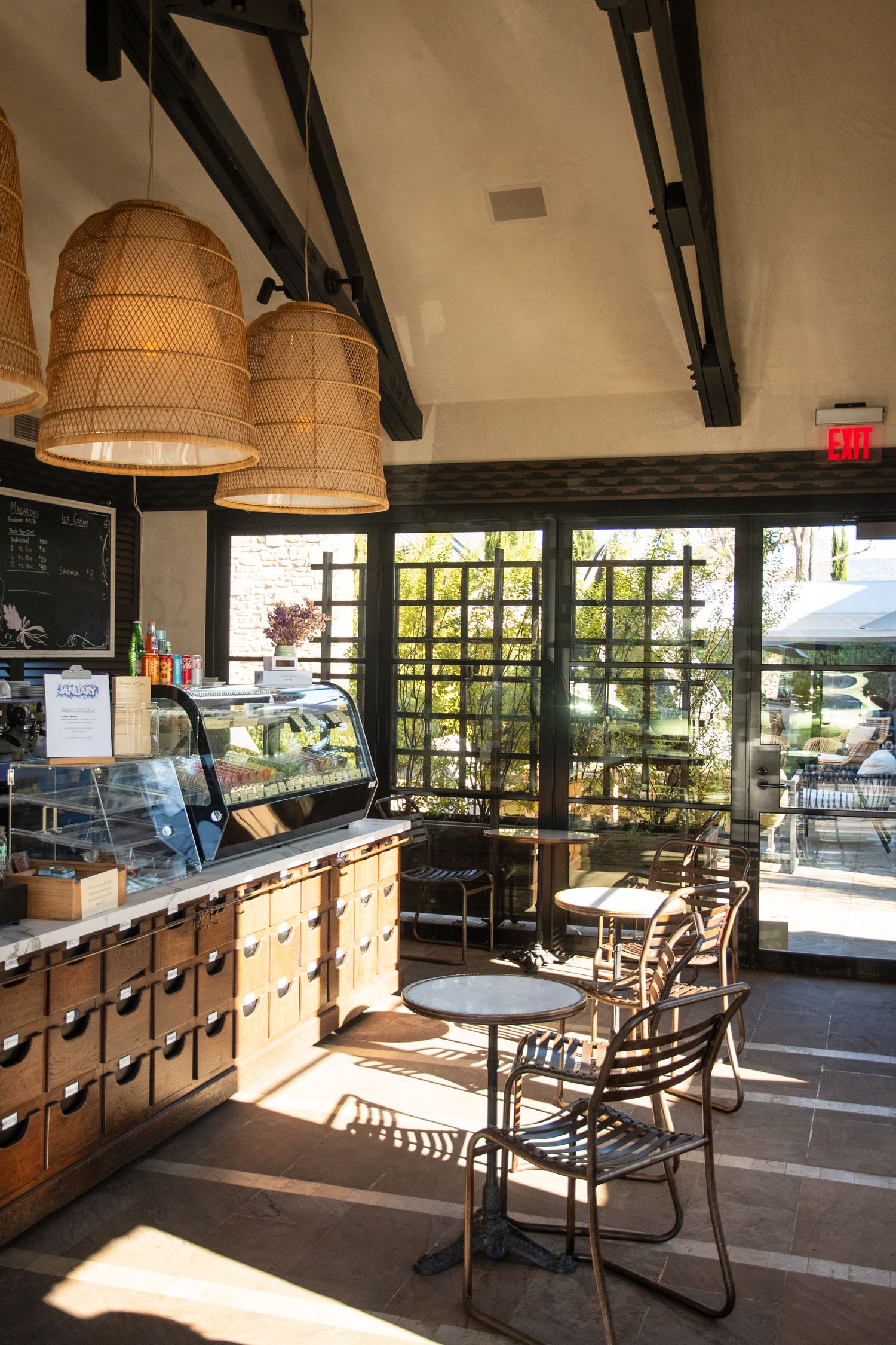 Sunlit cafe interior with wooden storage drawers, pendant lamps and window seating.